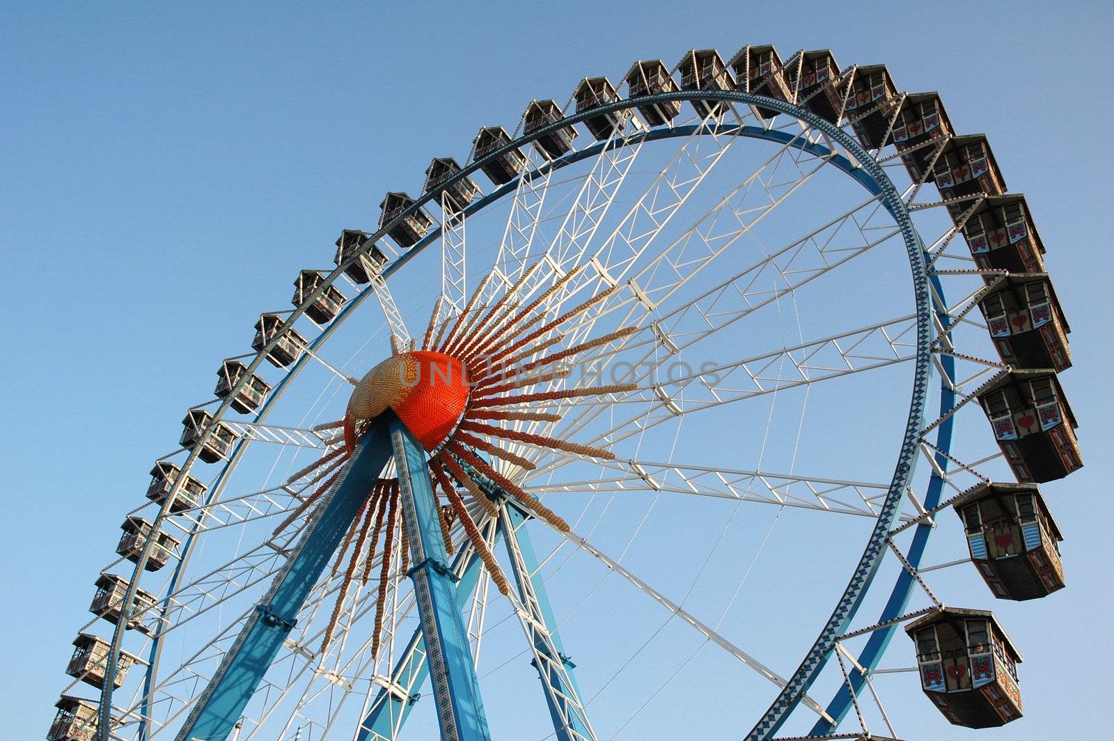 Ferris wheel against bright blue sky on amusement park