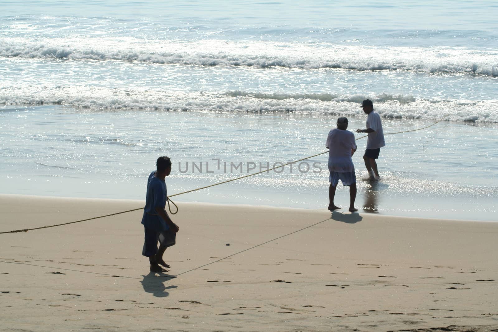 Fishermen pulling in a net from the beach