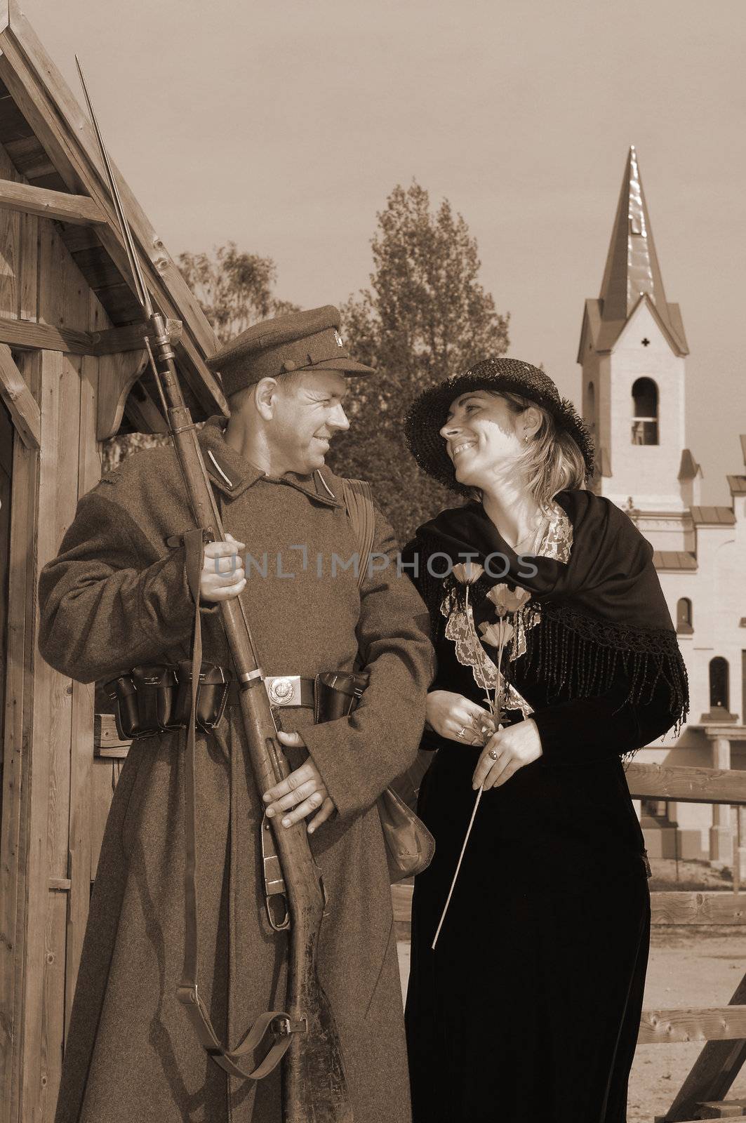 Old style picture with woman in dress and man in soldier uniform with weapon. Costumes are authentic to the ones weared in time of  World War I.