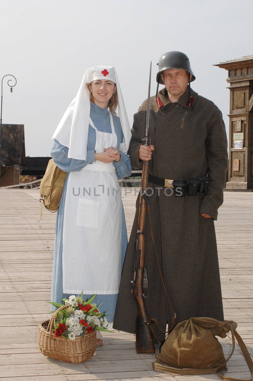 Old style picture with woman in nurse costume and man in soldier uniform with weapon. Costumes are authentic to the ones weared in time of  World War I.