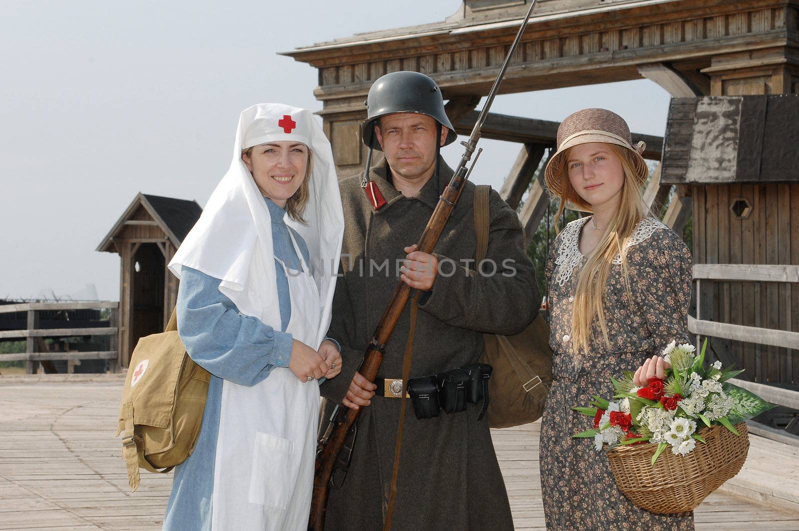 Old style picture with woman in nurse costume, her daughter in flowered dress and man in soldier uniform with weapon. Costumes are authentic to the ones weared in time of  World War I.