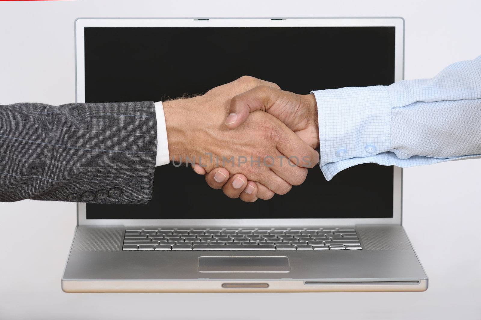 Caucasion hand shakes Indian hand over laptop computer