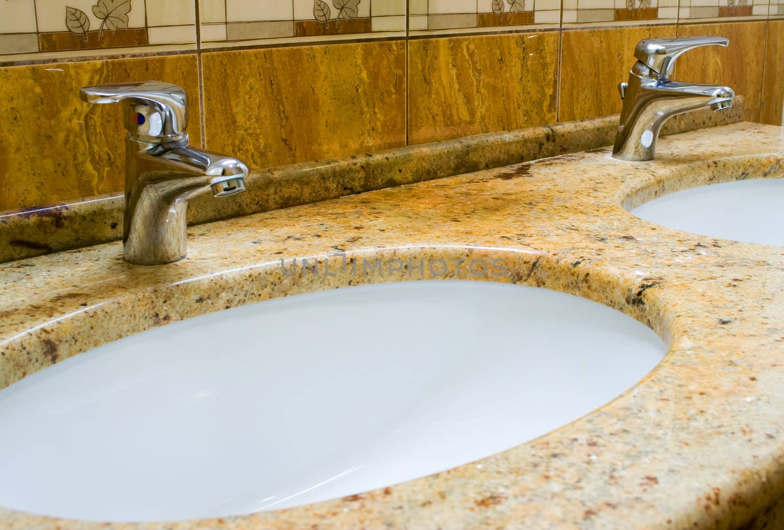 Washbowls in marble with closed water taps in bathroom.