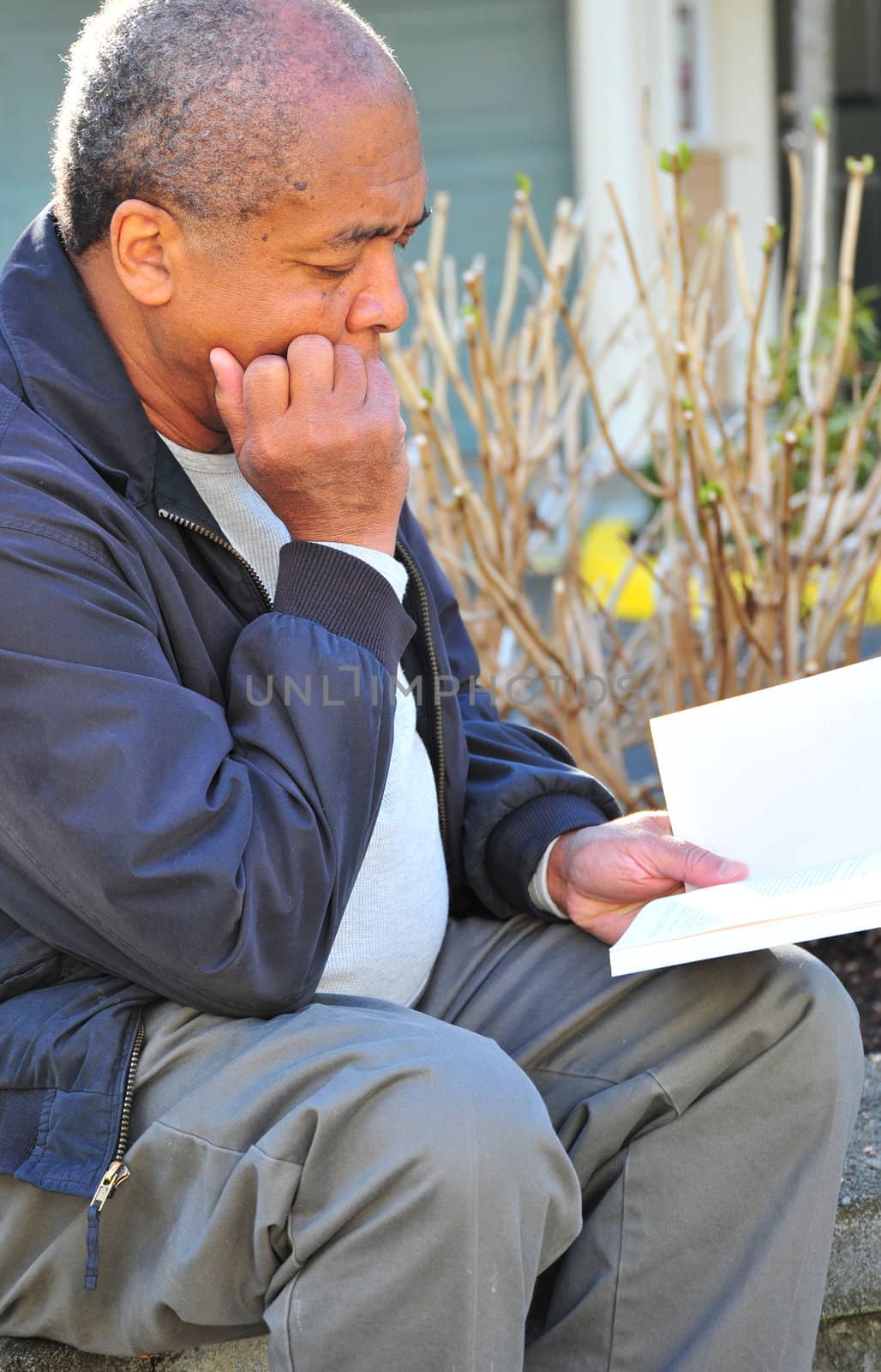 African american man reading a book outdoors.