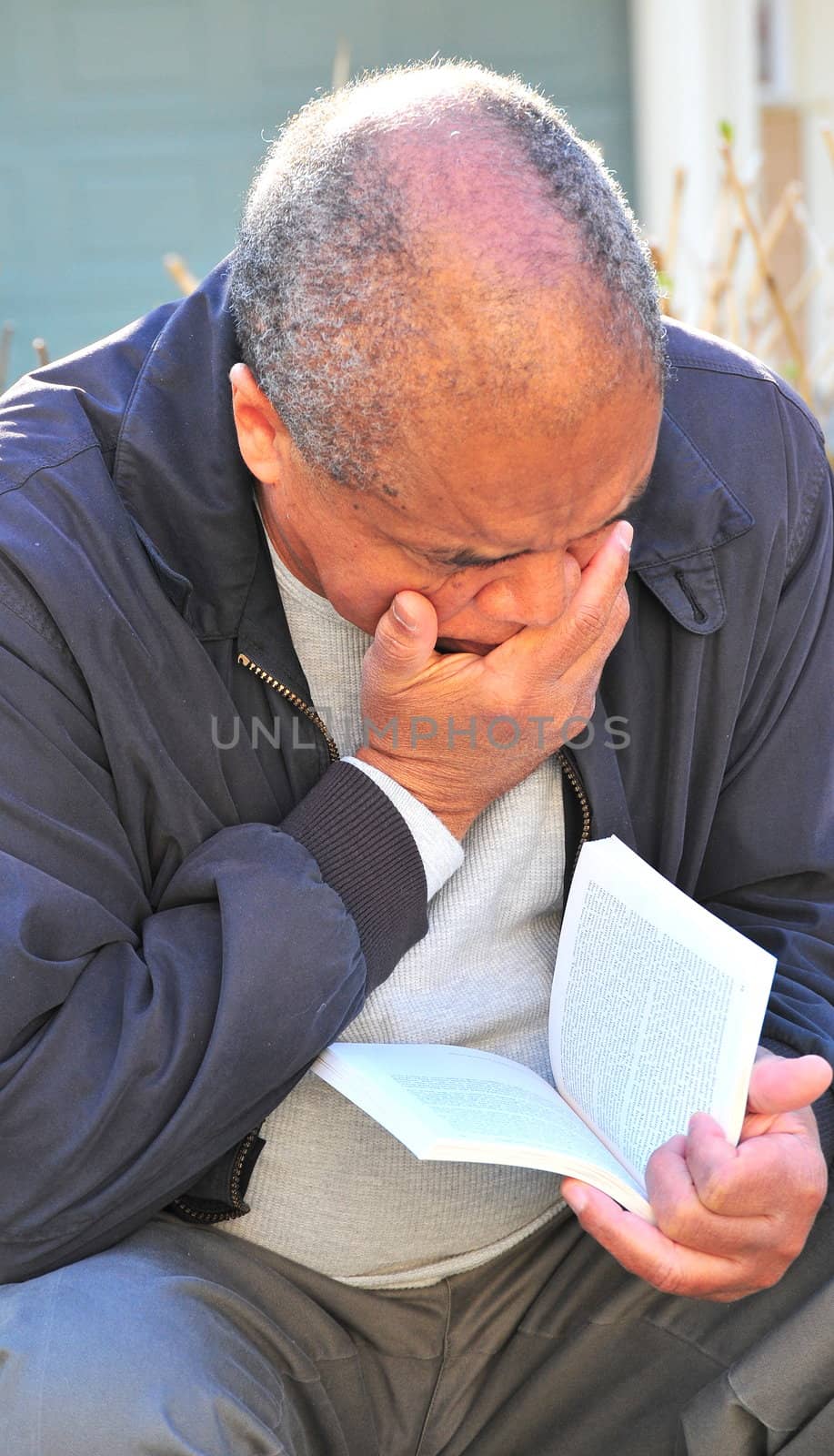 African american man reading a book outdoors.