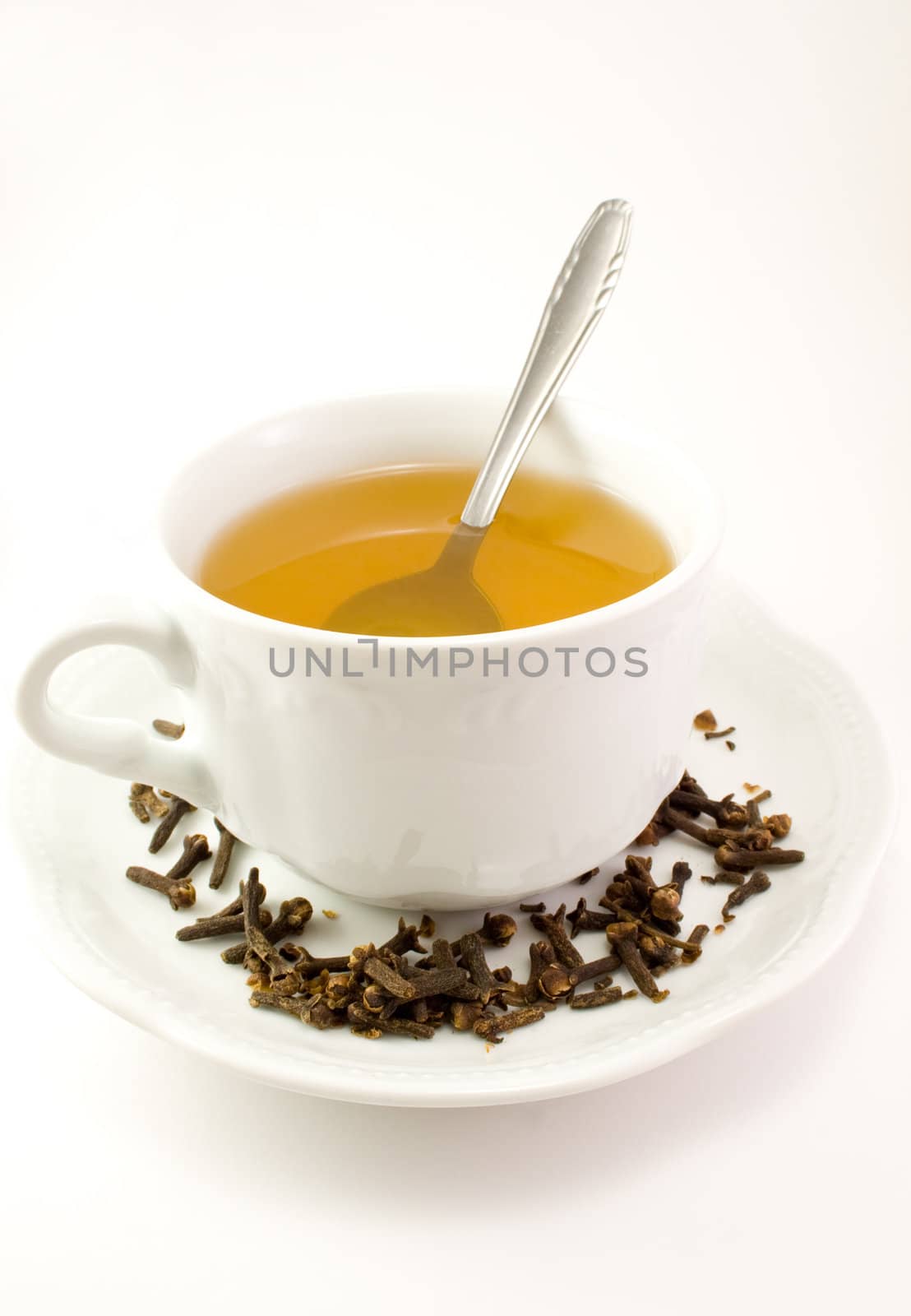 Cup with tea, spoon, plate and decoration on it.