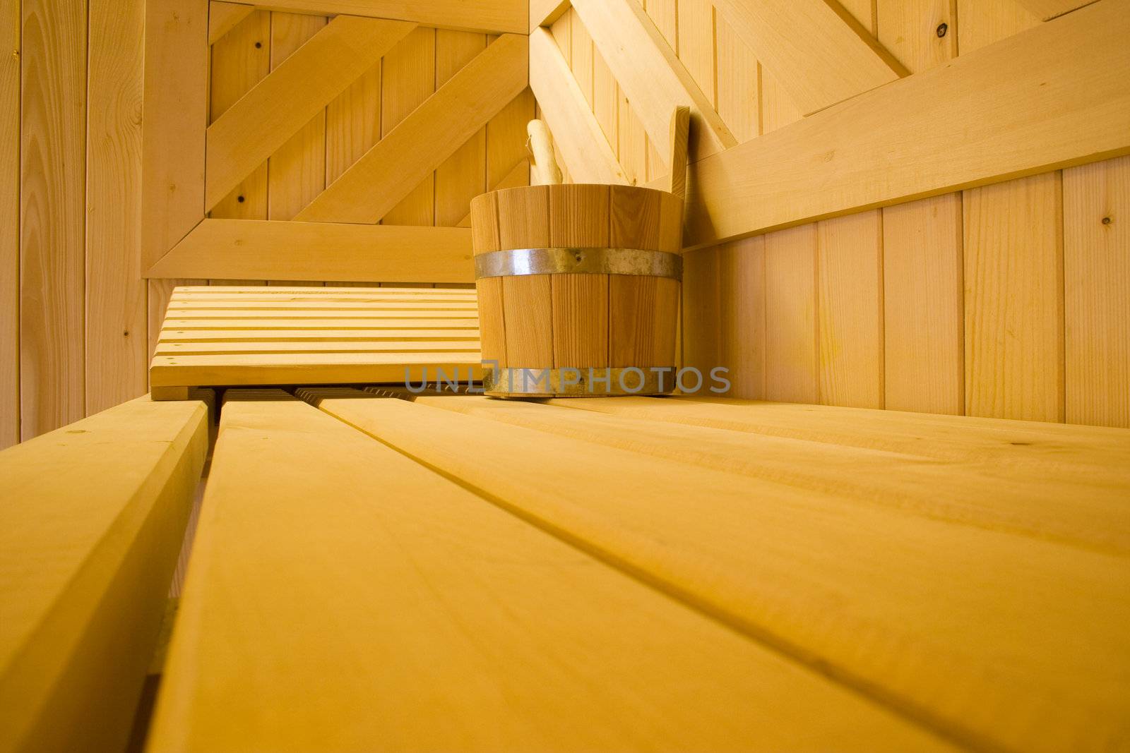 Bucket for water and pillow on bench in Finnish sauna.