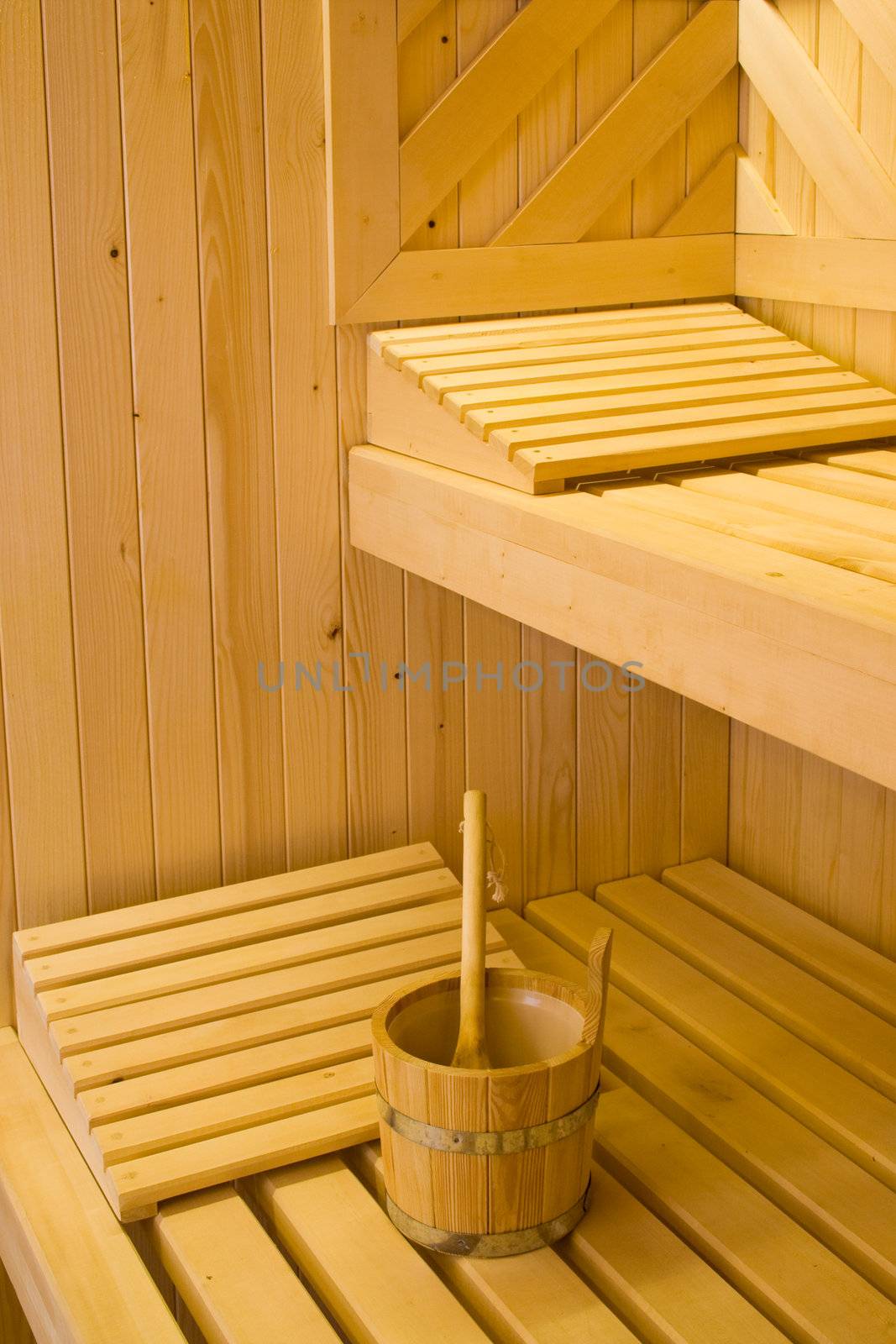 Bucket for water and two pillows on bench in Finnish sauna.