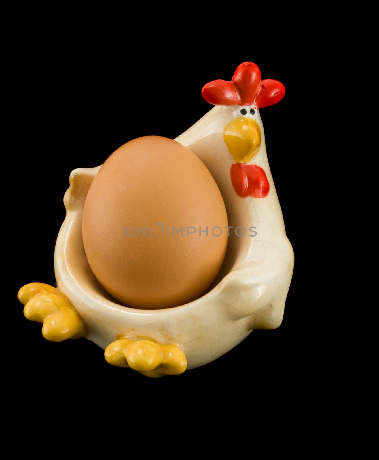 Chicken holding egg, isolated on black background.