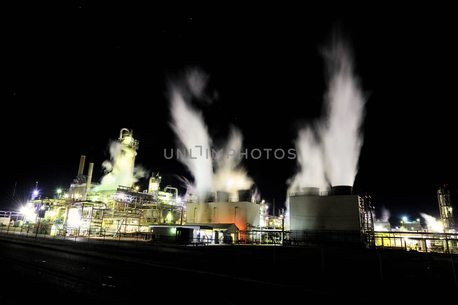 Graphic image of an industrial plant at night with steam flowing upward, shot at night with visible stars