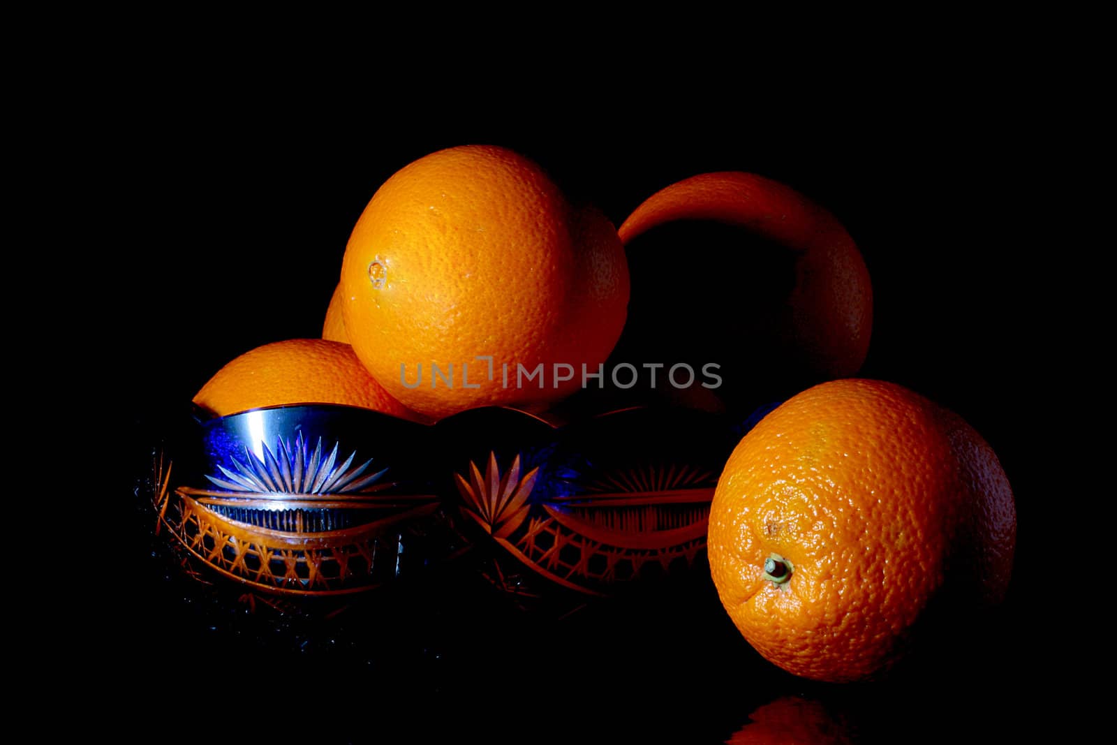 Orange in a dark blue glass vase on a black background.