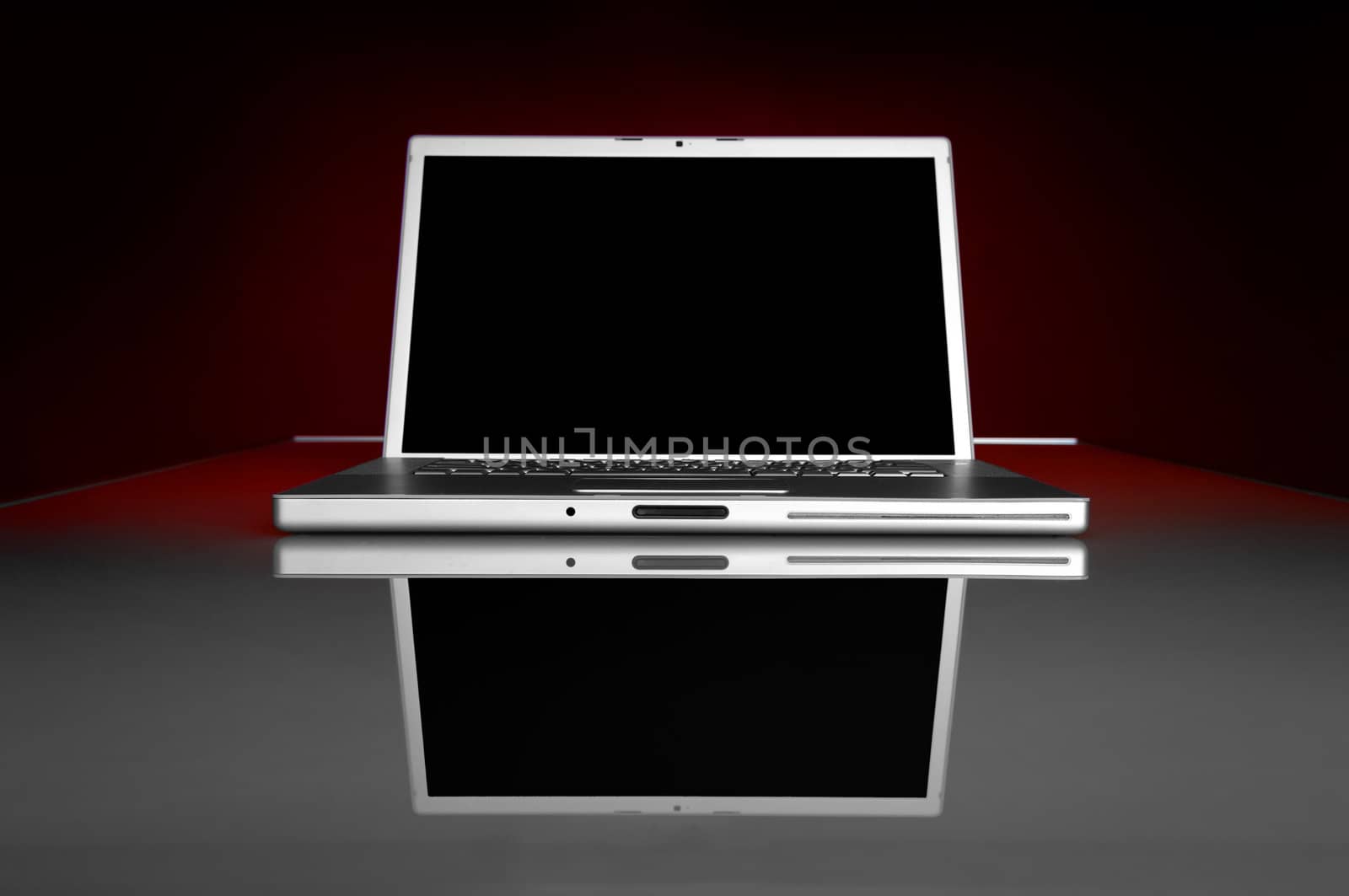 Image of a dark screen laptop on a glass table with reflection
