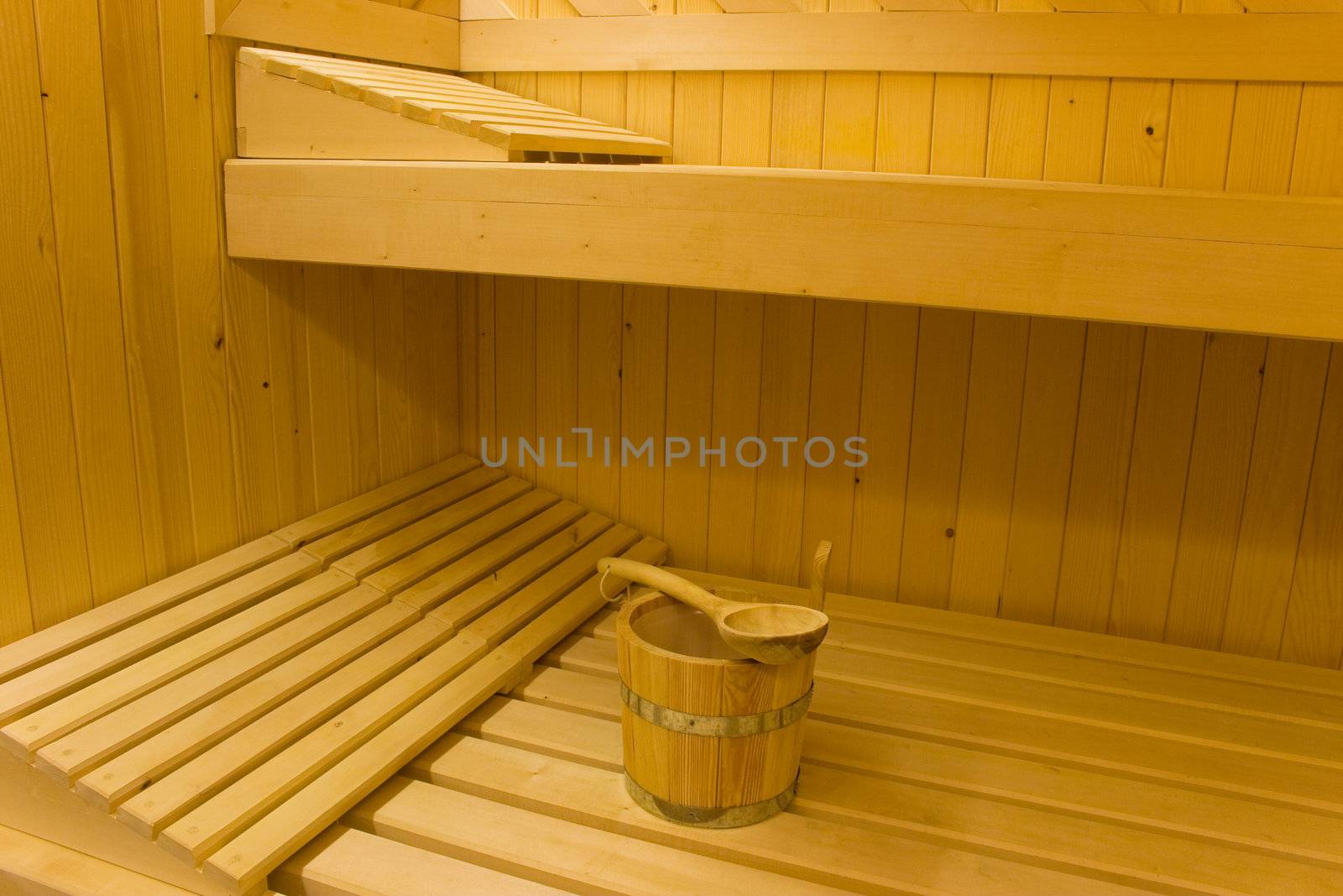 Bucket for water and pillows on benches in Finnish sauna.