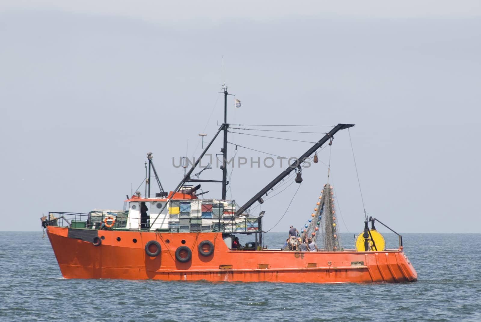 Red fishing boat in the sea, with blue sky.
