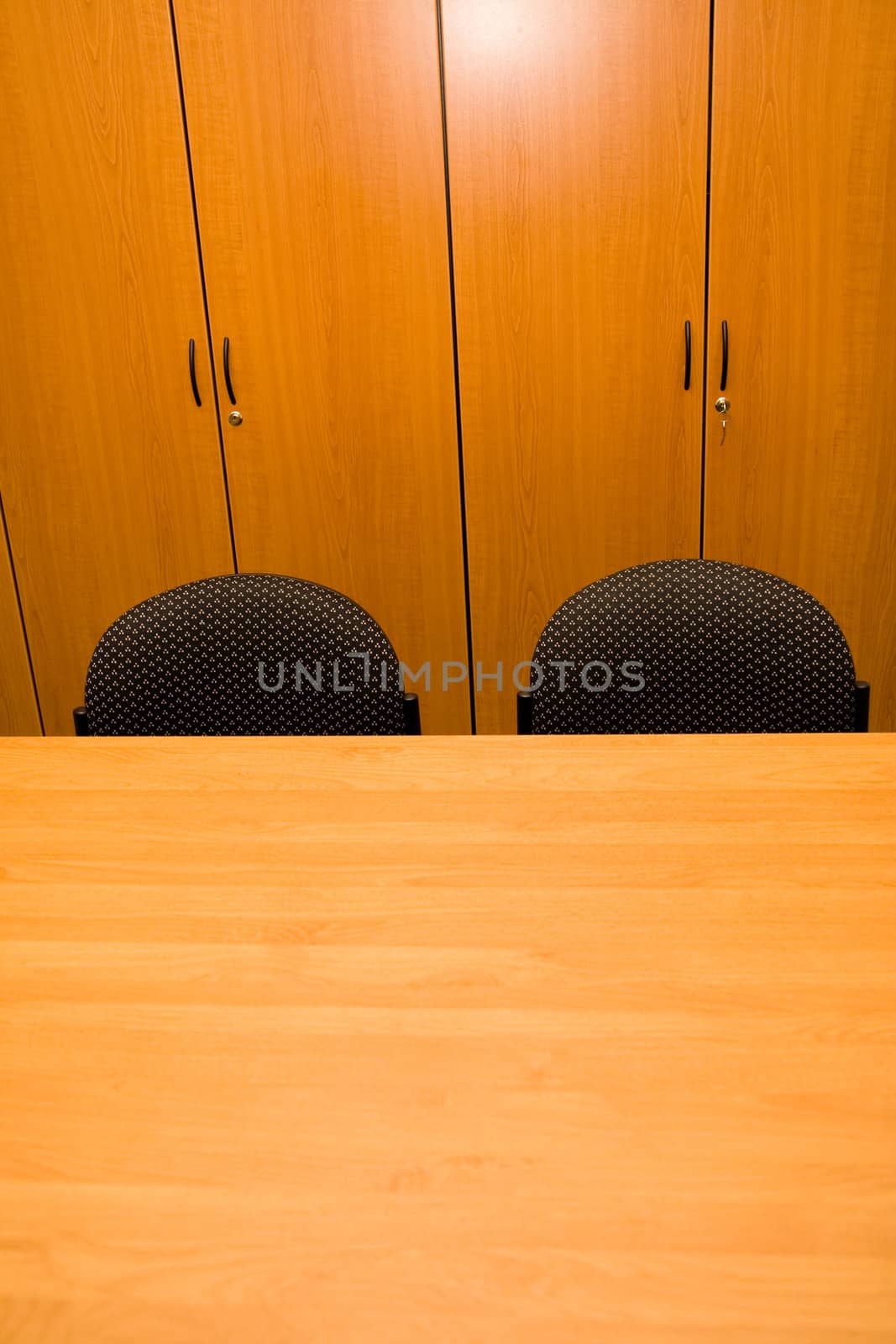 Detail of wooden closets, table and chairs in an office.