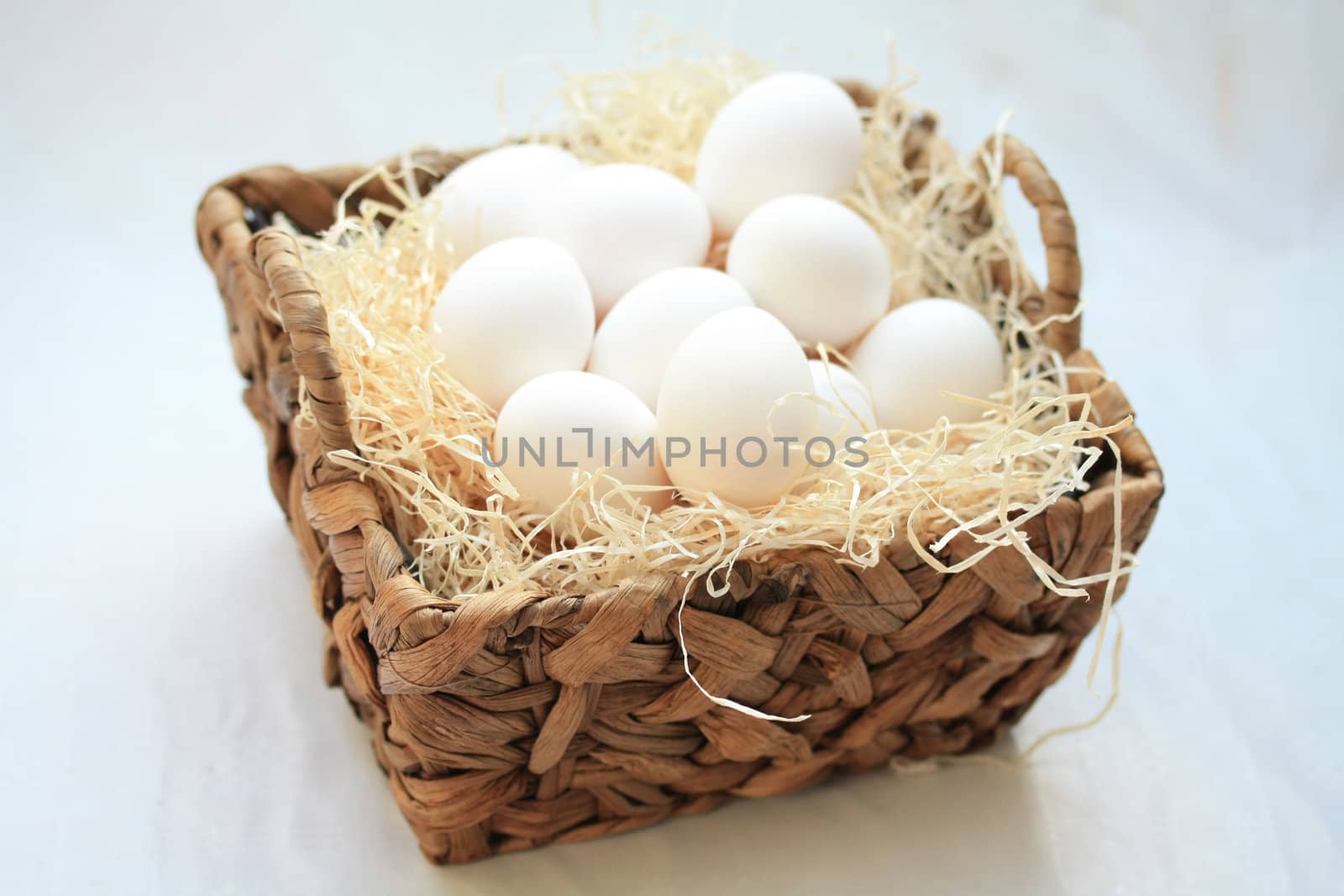 Wicker basket with hay and white eggs