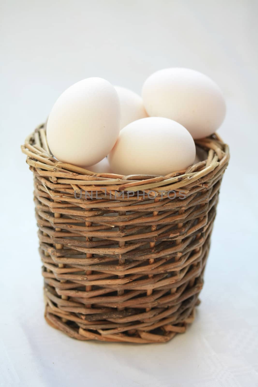 A round wicker basket with white eggs