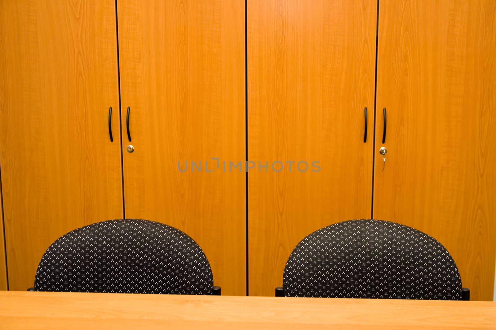 Detail of wooden closets, table and chairs in an office.