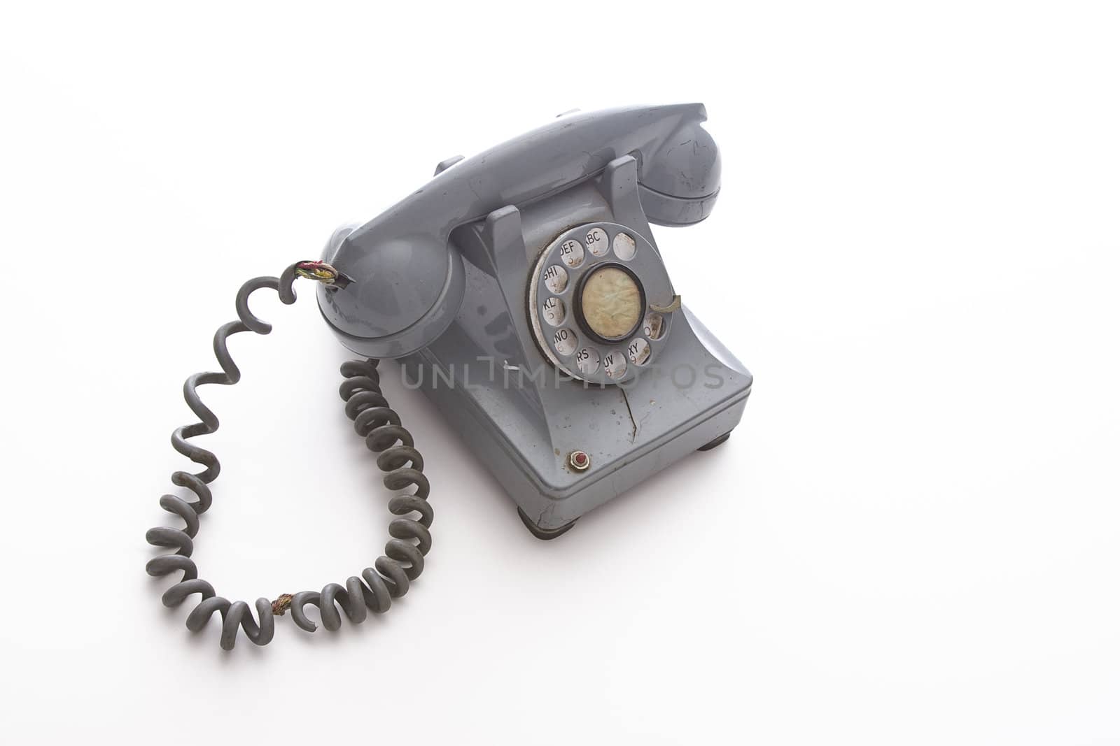 dirty vintage gray rotary phone with crack casing and expose wired