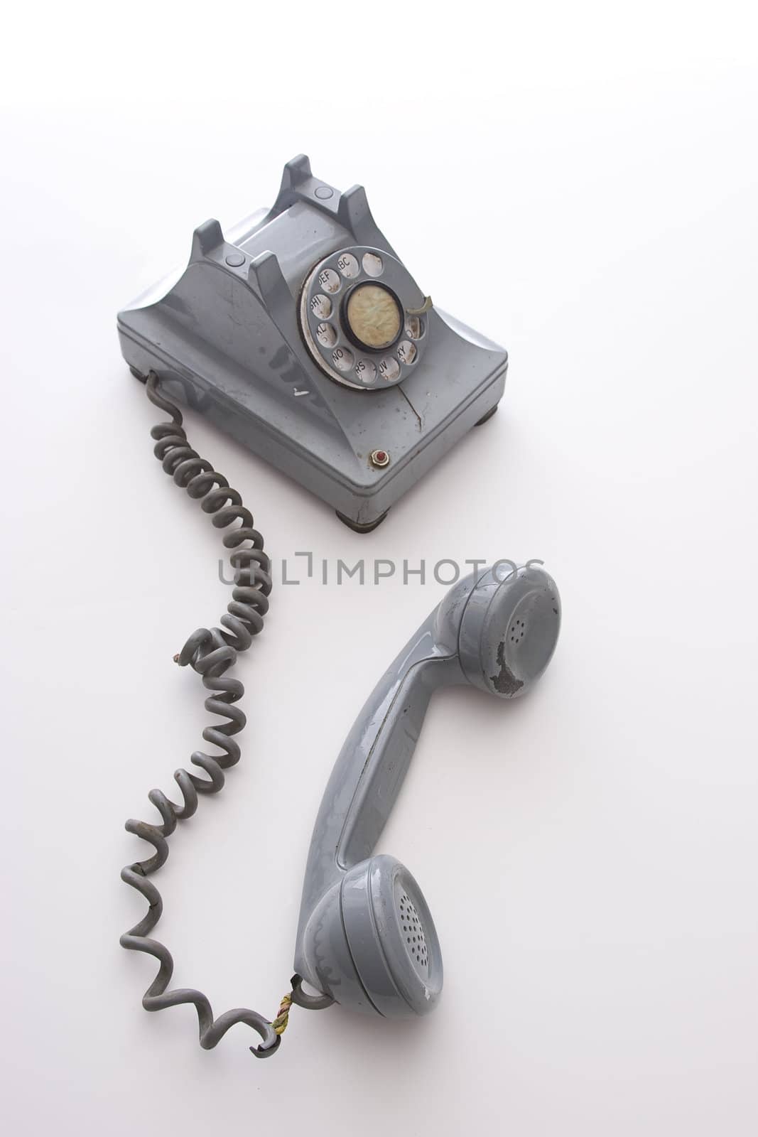 dirty vintage gray rotary phone with crack casing and expose wired, unhooked and left there