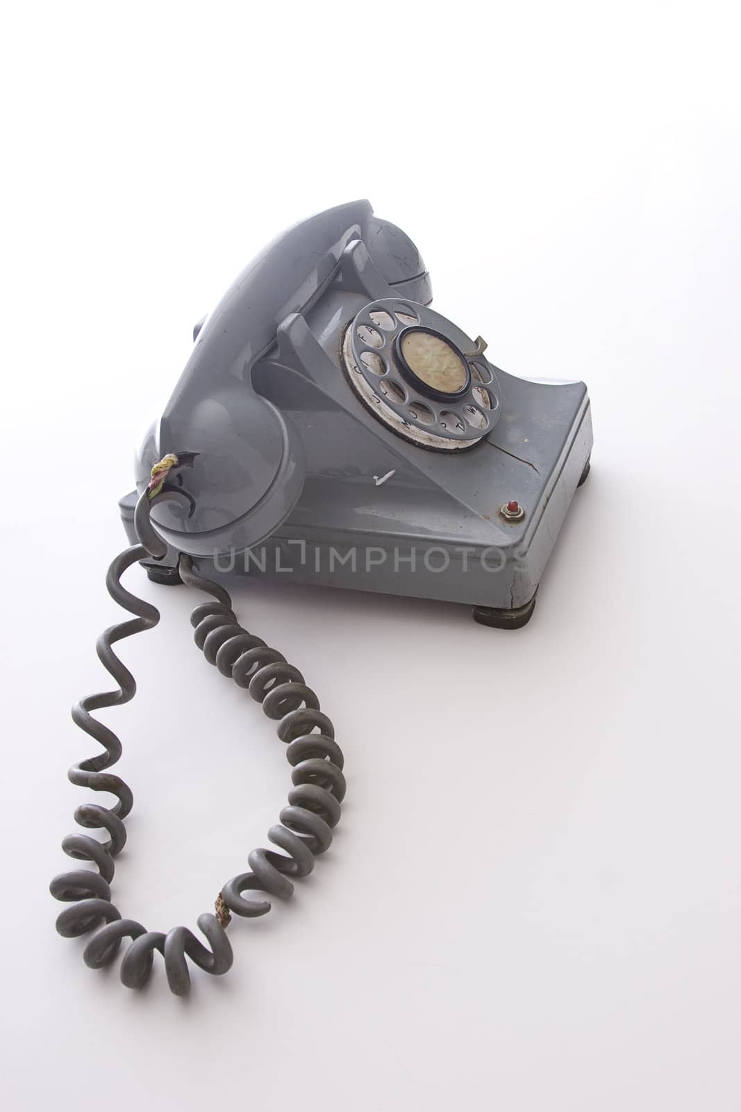 dirty vintage gray rotary phone with crack casing and expose wired
