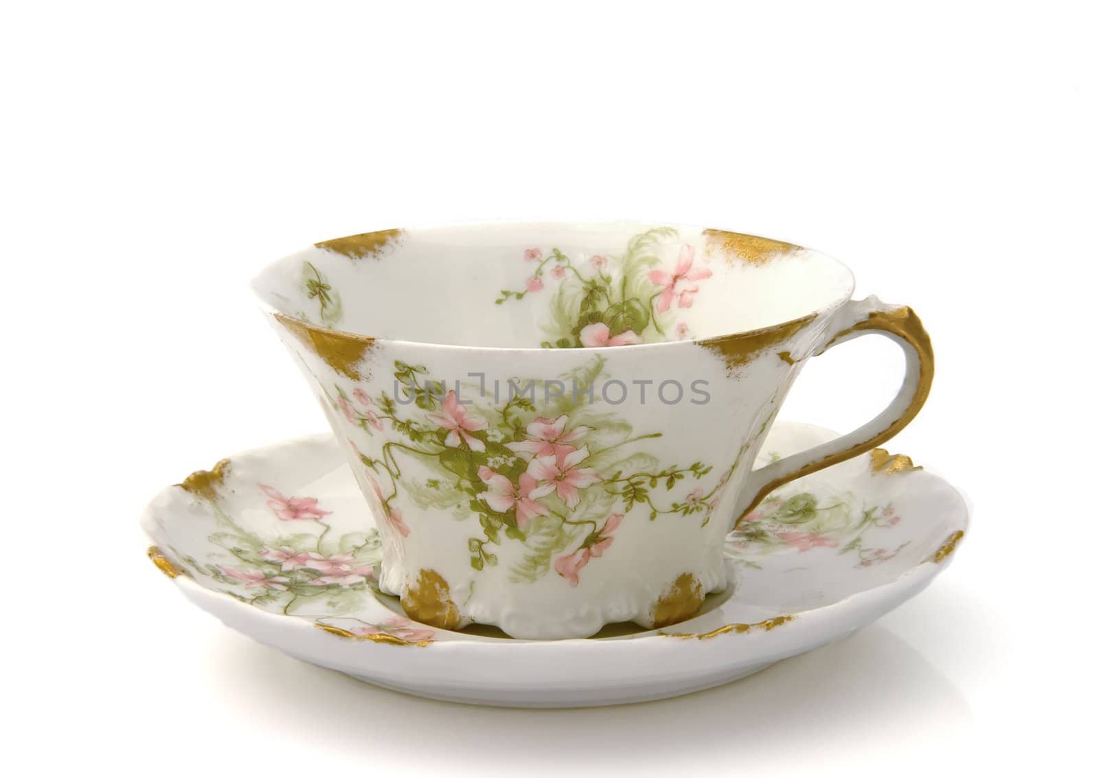 Antique teacup and saucer with a floral pattern isolated on white 