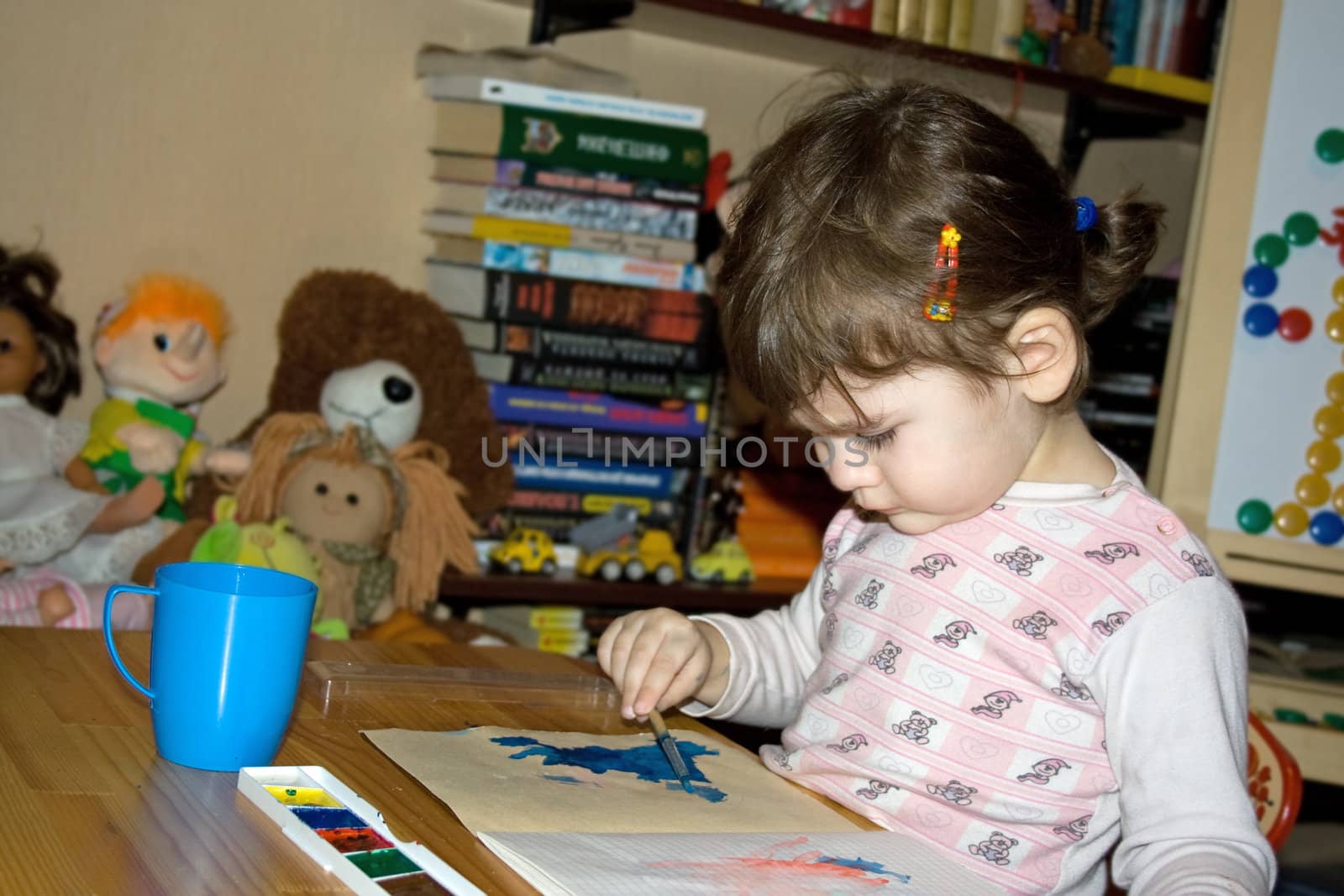 serious girl drawing with colours and brush in her own room