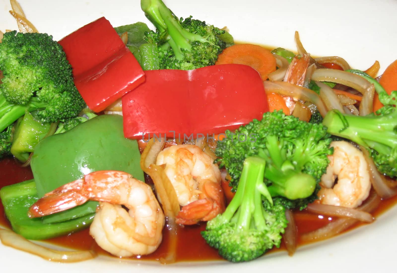 Plate of shrimp stir fry with broccoli and red peppers, against a white background