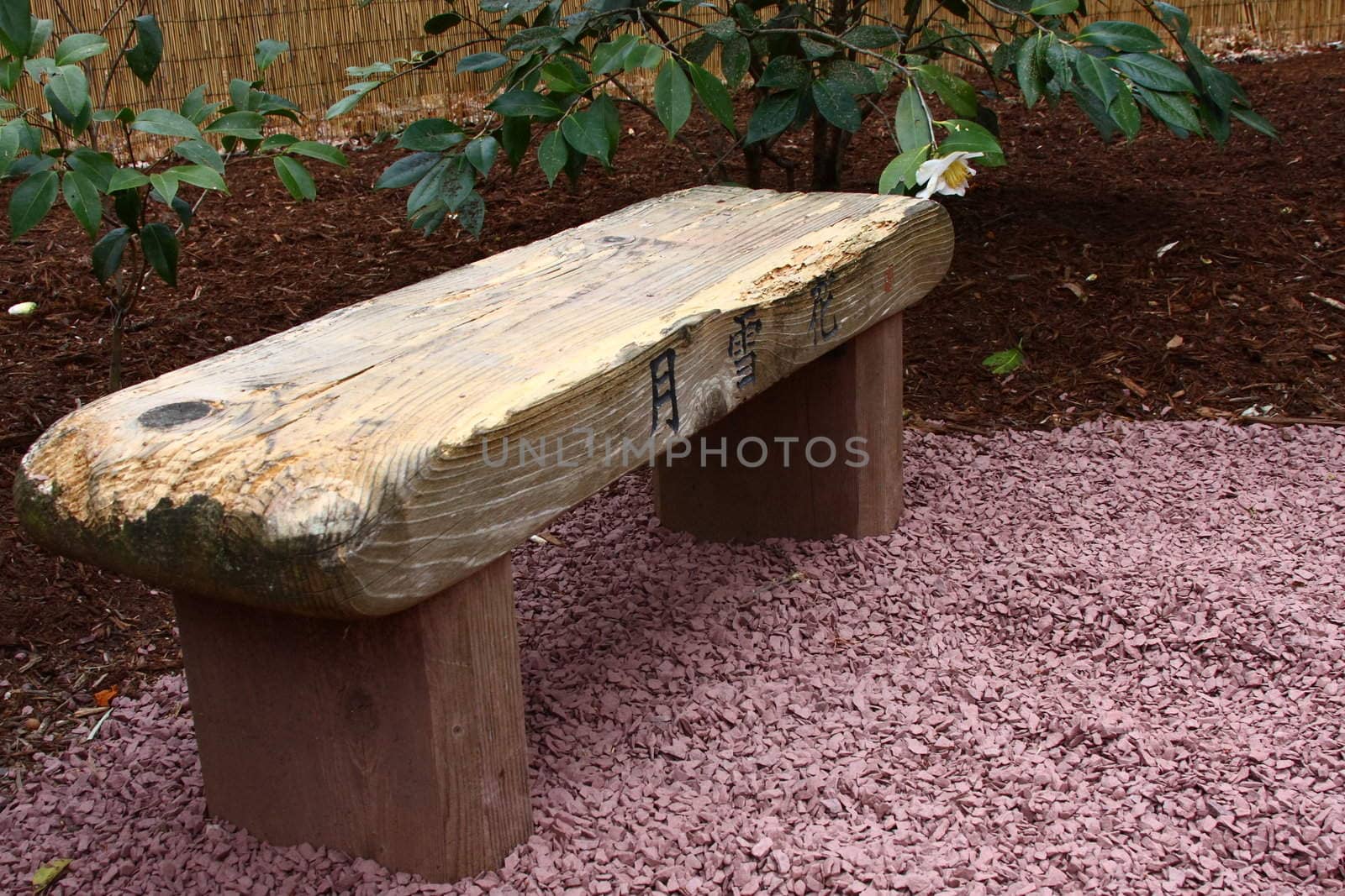Wooden bench in a garden with Japanese inscriptions.