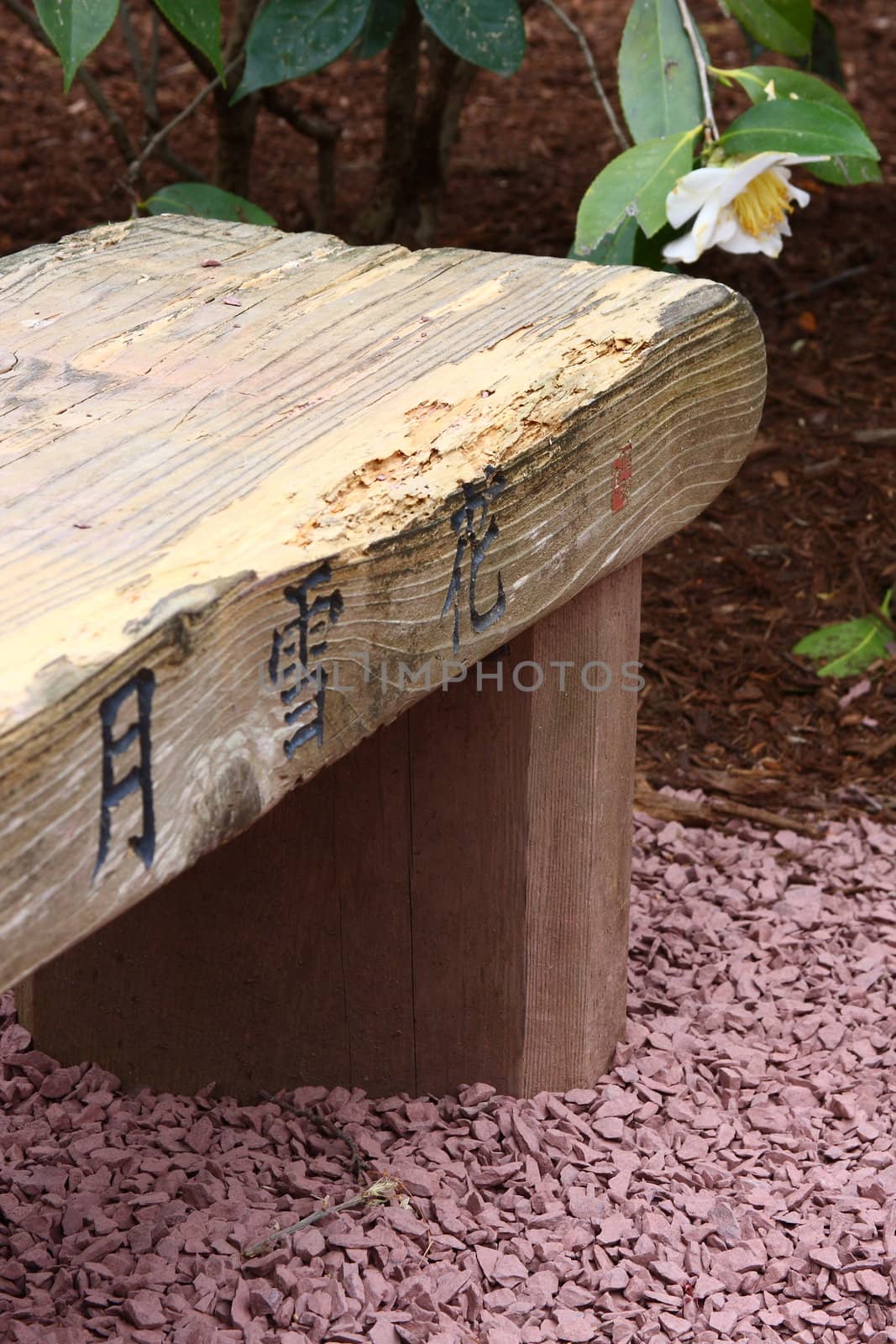 Wooden bench in a garden with Japanese inscriptions.