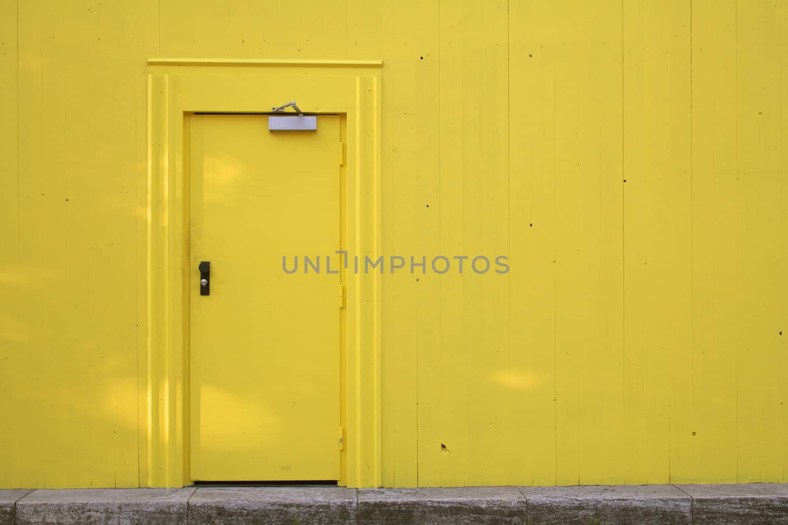 Metal door in a wooden wall. Everything painted yellow. Lots of copyspace.