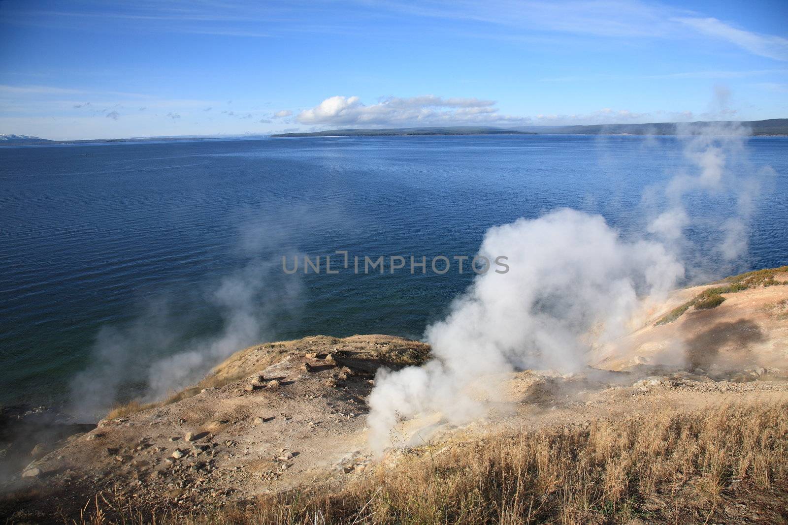 Mountain lake with steam rising from hot springs in foreground