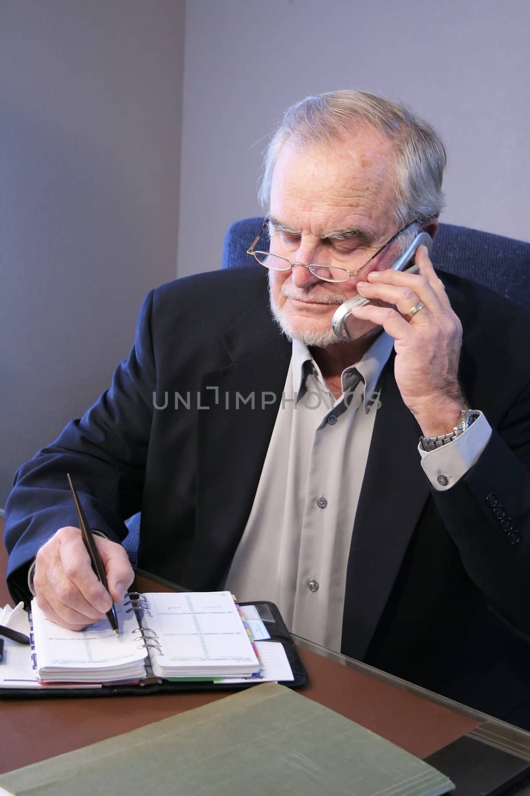 Mature Business Executive on phone taking notes