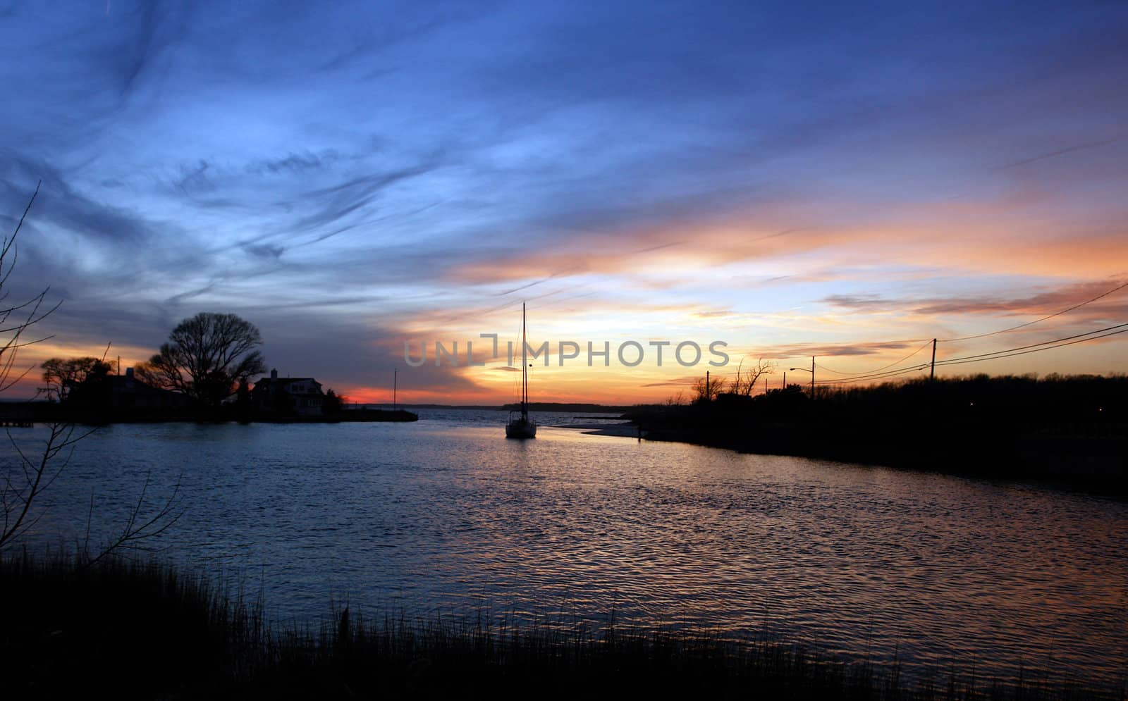 Sailboat sailing towards sunset on a calm evening