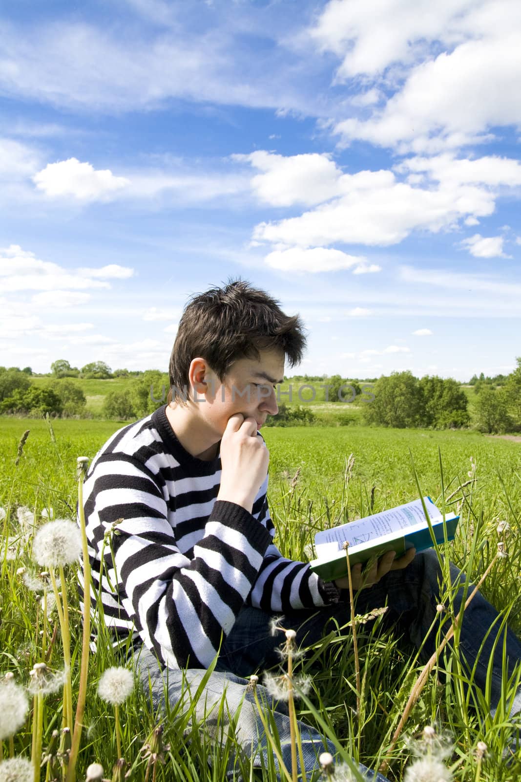 Boy reading a book on the grass. Time before examination
