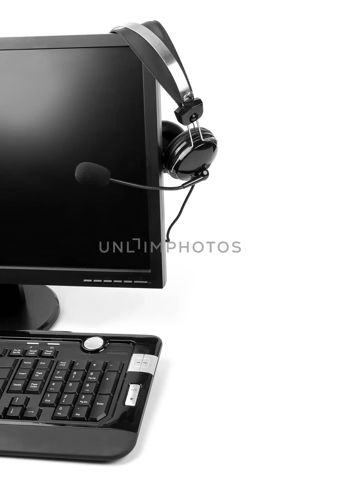 Computer with VOIP headset hanging on the screen, isolated on white background. Internet communications, VOIP (Voice Over Internet Protocol), call-center concepts. 