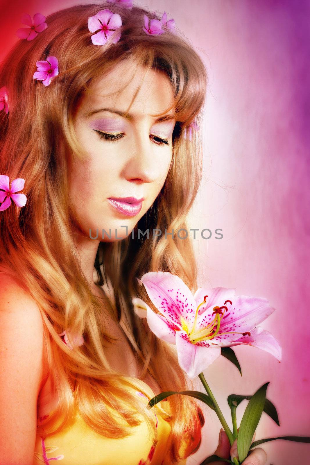 A pretty girl holds a single pink lily flower