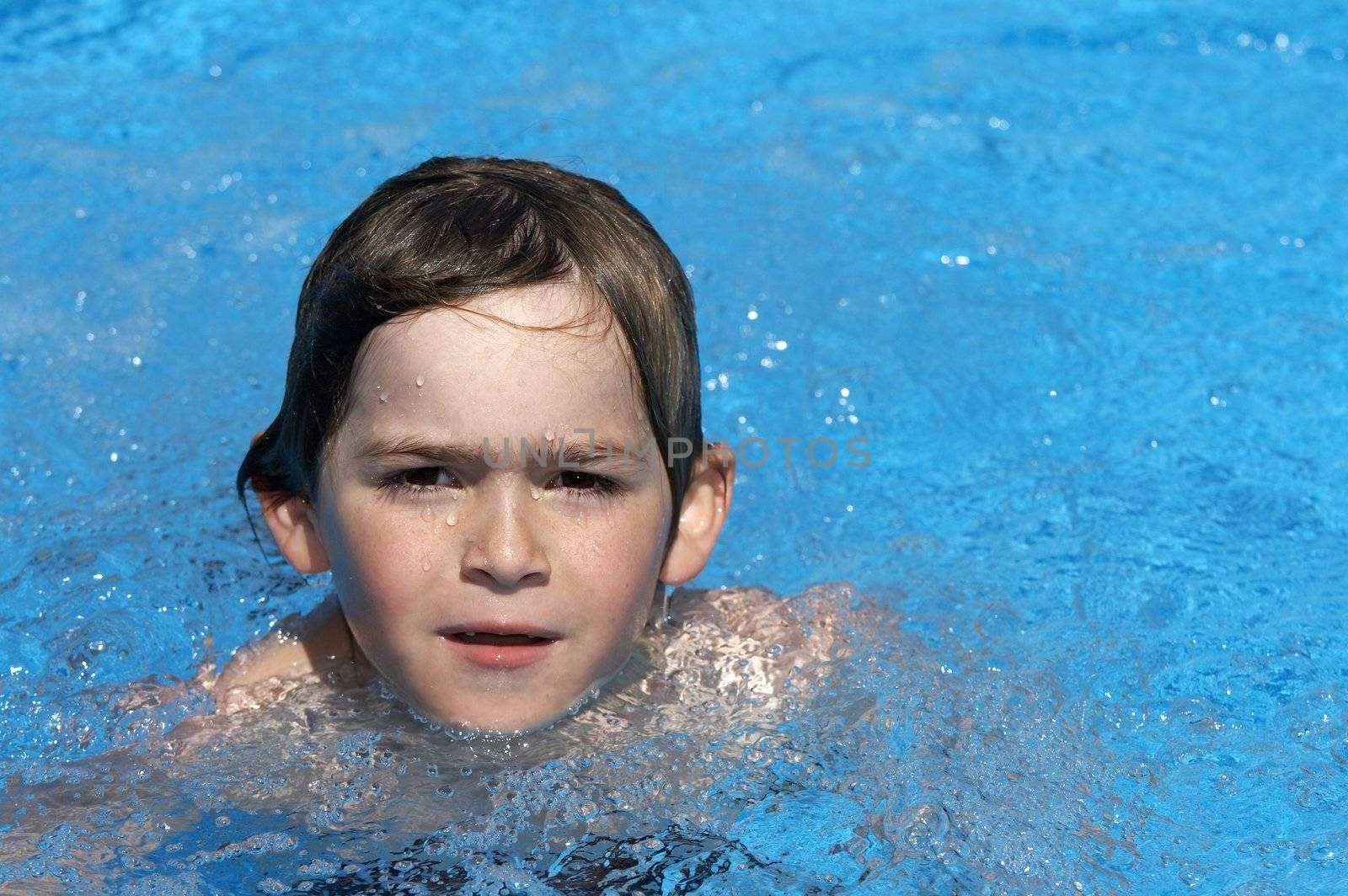 a boy playing in a pool of water during the summer