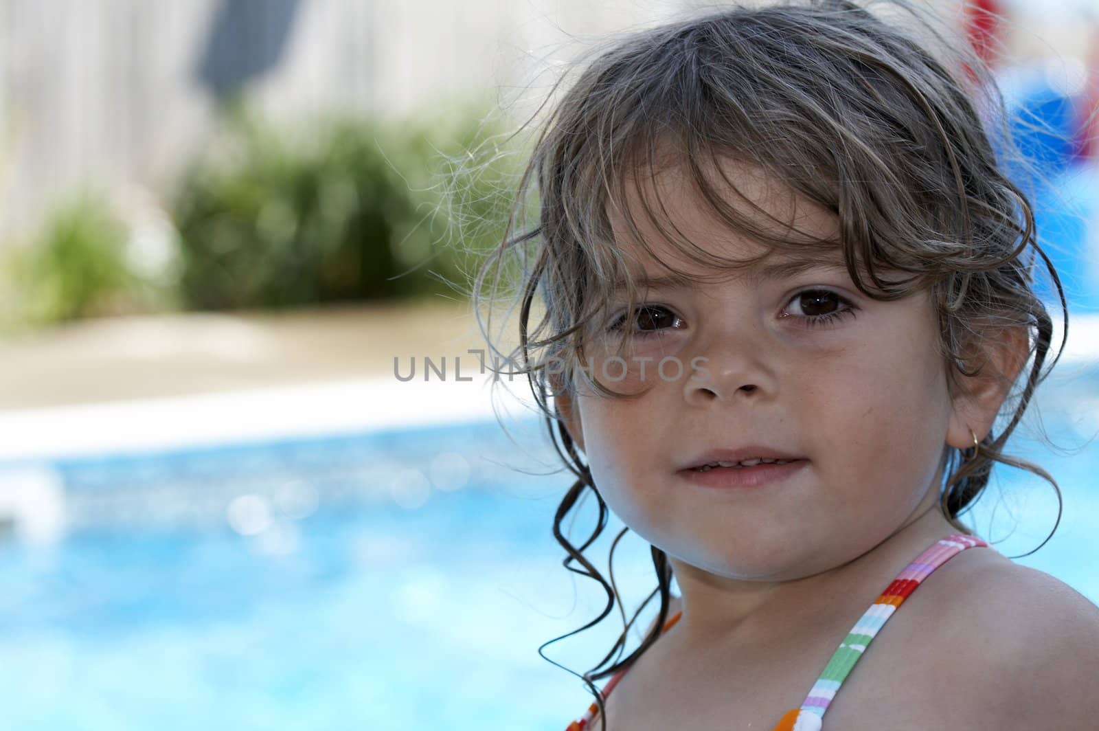 a young girl looking at camera buy a pool