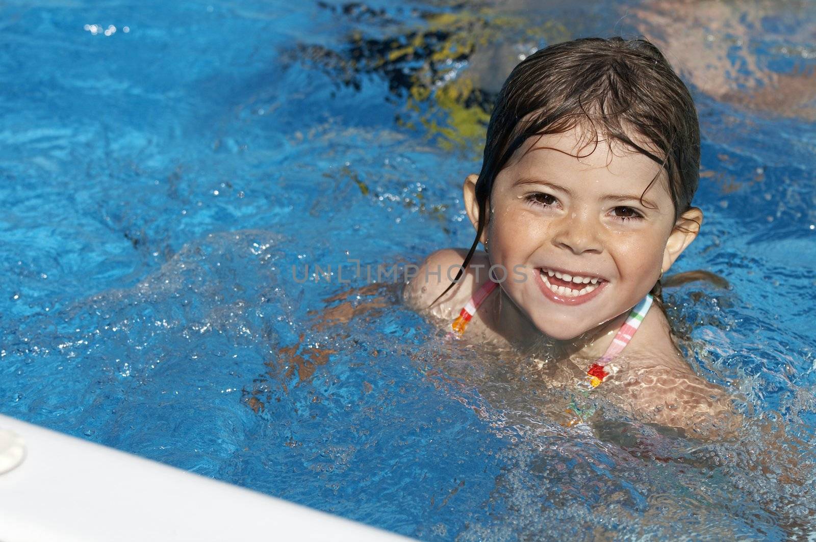 a cute little girl looking at pool water during the summer