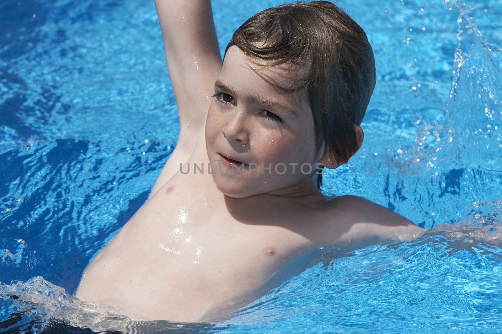 a boy playing in a pool of water during the summer