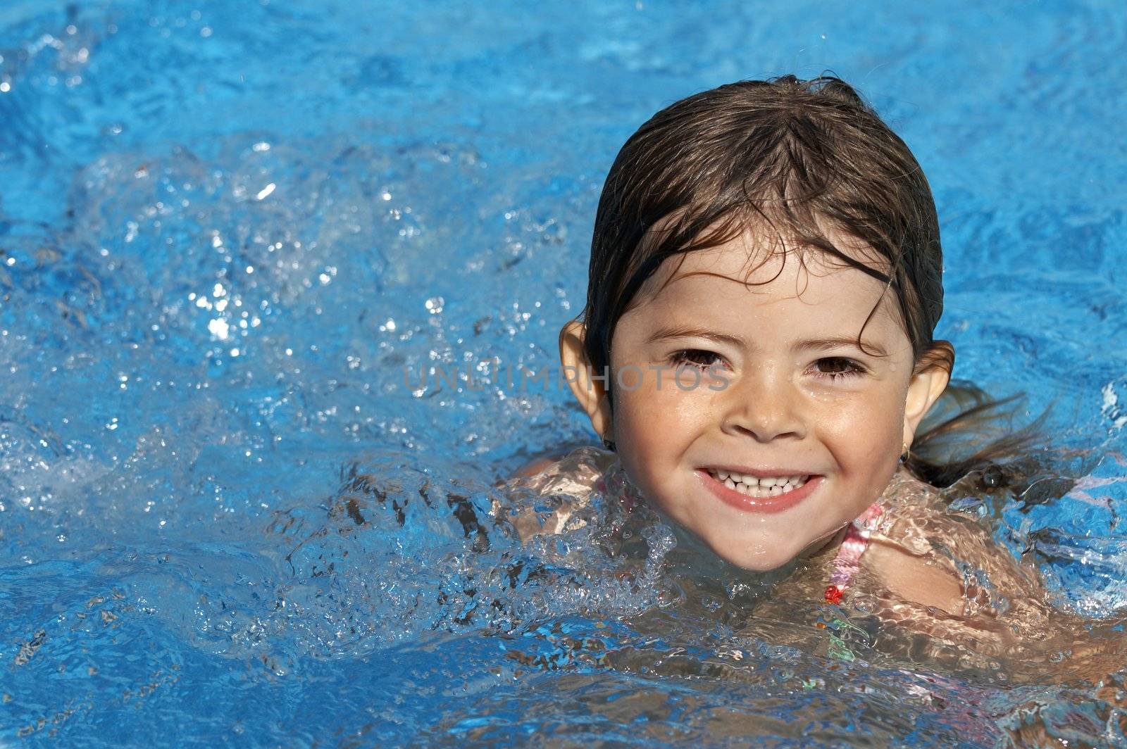 a cute little girl in pool water during the summer