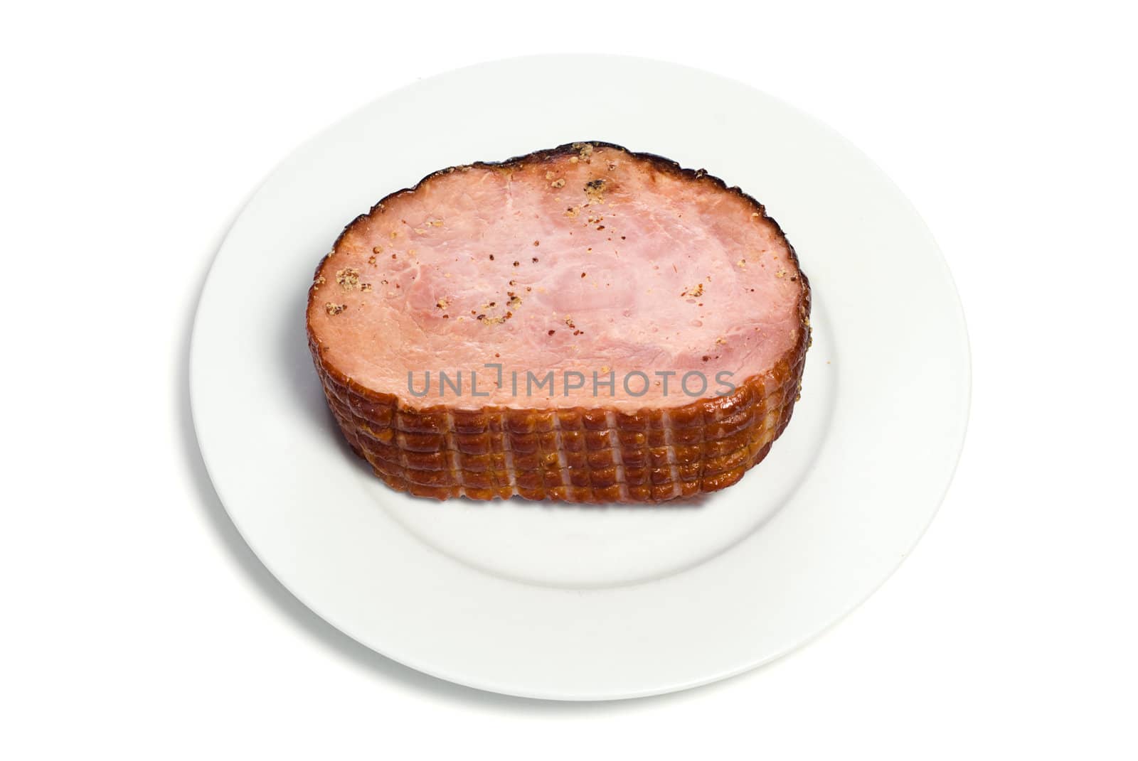 A cooked ham on a white plate with spices on top, isolated