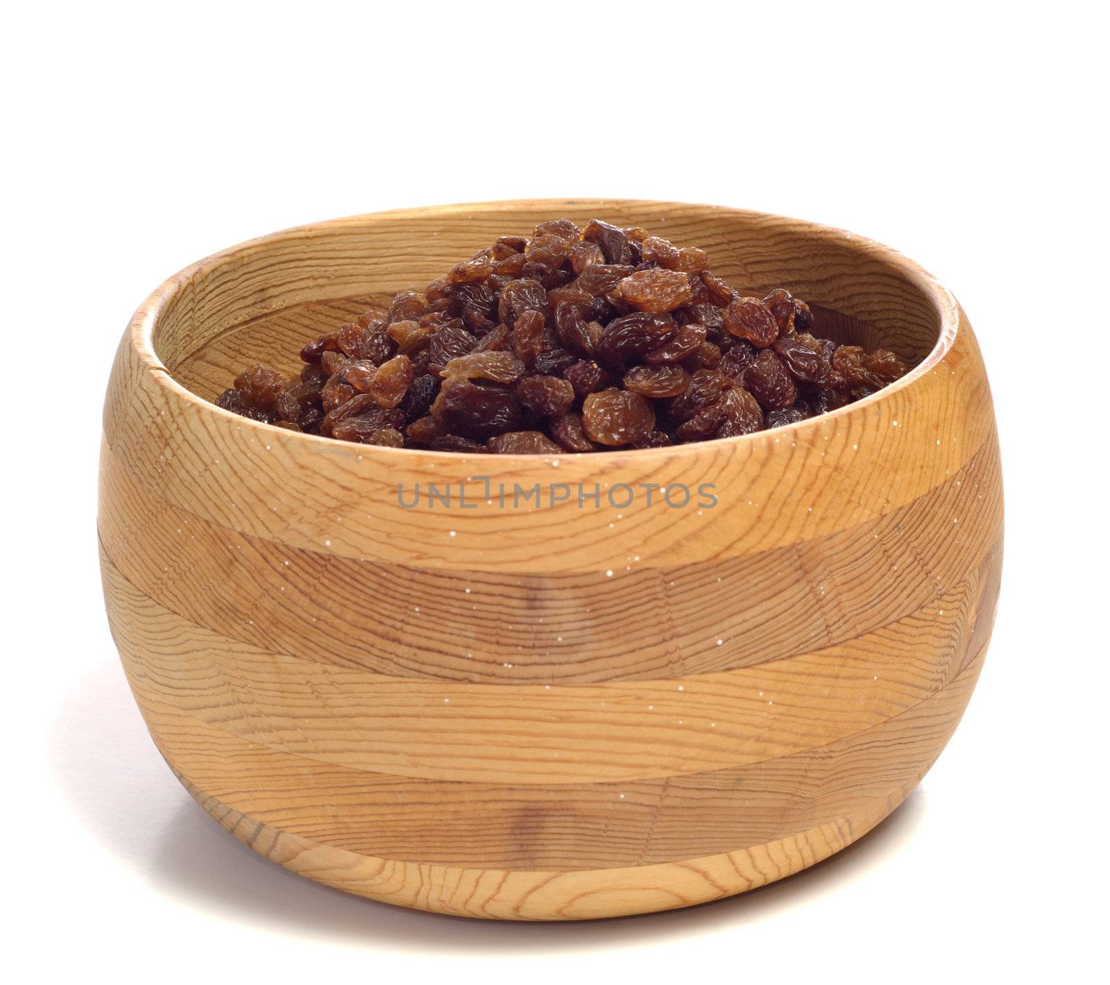 A pile of raisins in a wooden bowl, isolated against a white background