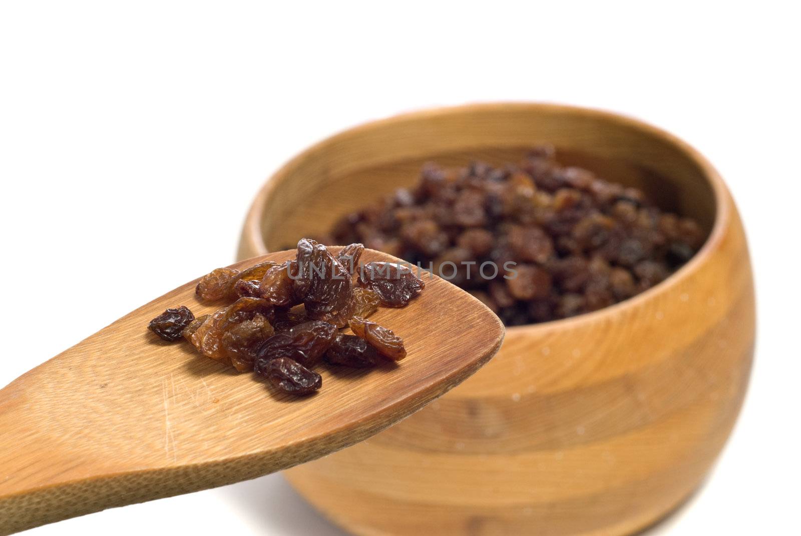 A wooden spoon full of raisins show of an ingredient for cookies or something, shot on white