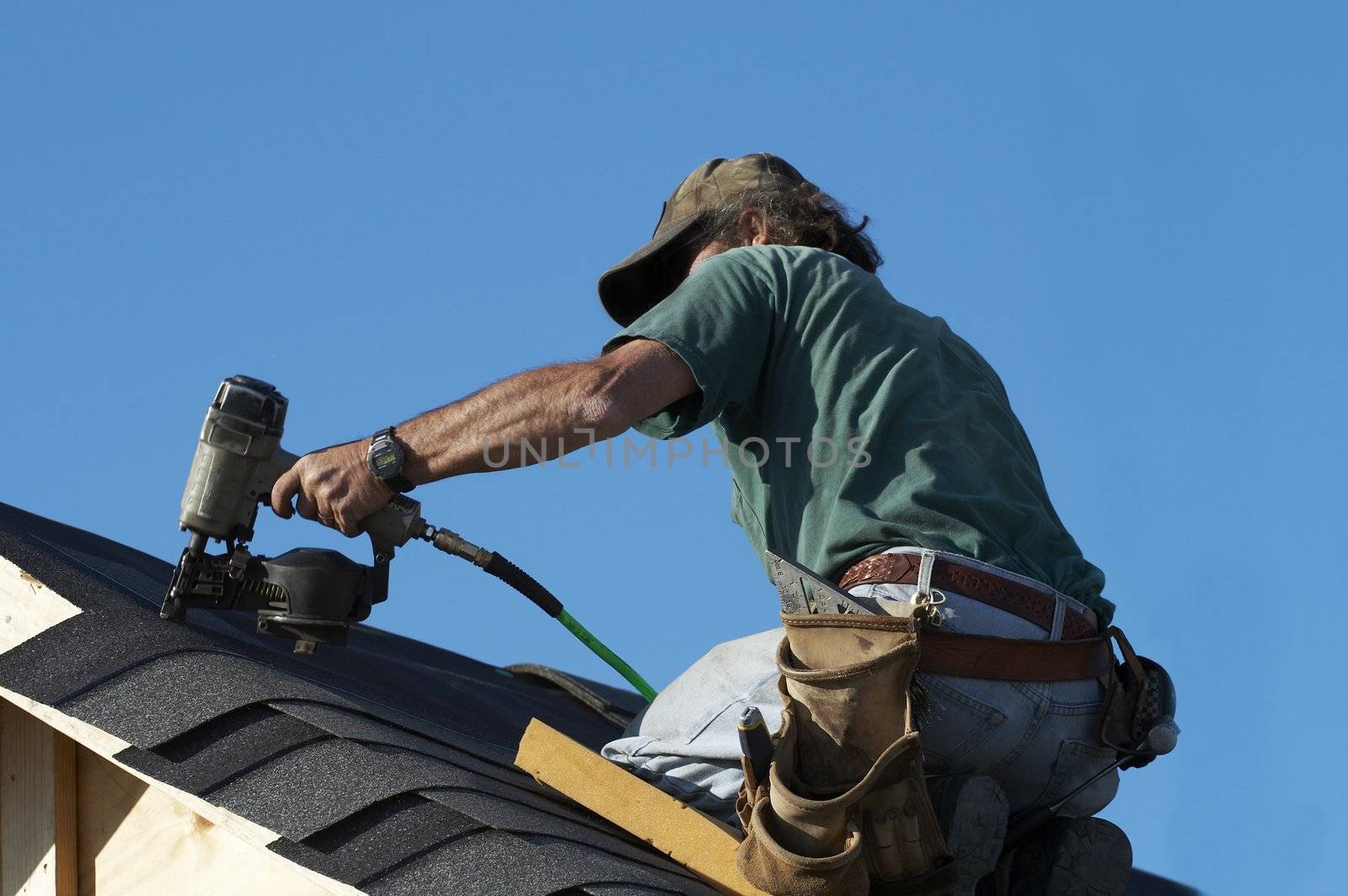 a roofer on a roof putting down shingles