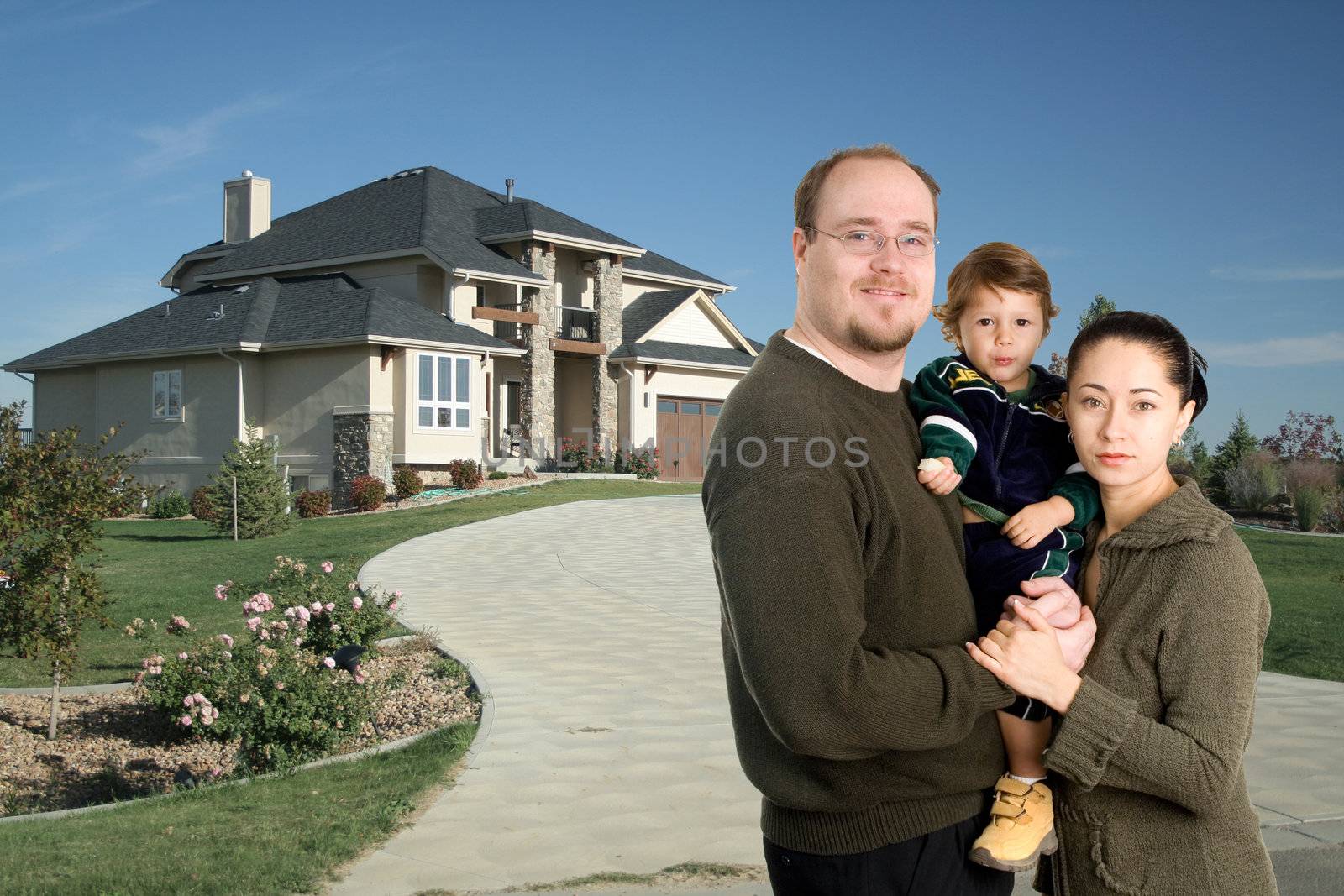 Young family standing together in front of luxury home