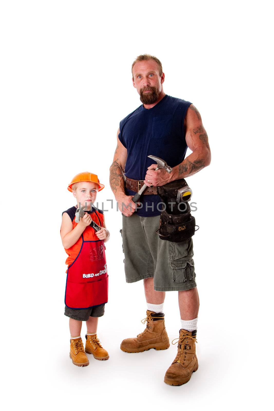 Caucasian middle aged father and cute young son ready to do a construction job. Man and boy wearing tool belt and holding hammers, wearing shorts and boots, standing, isolated.
