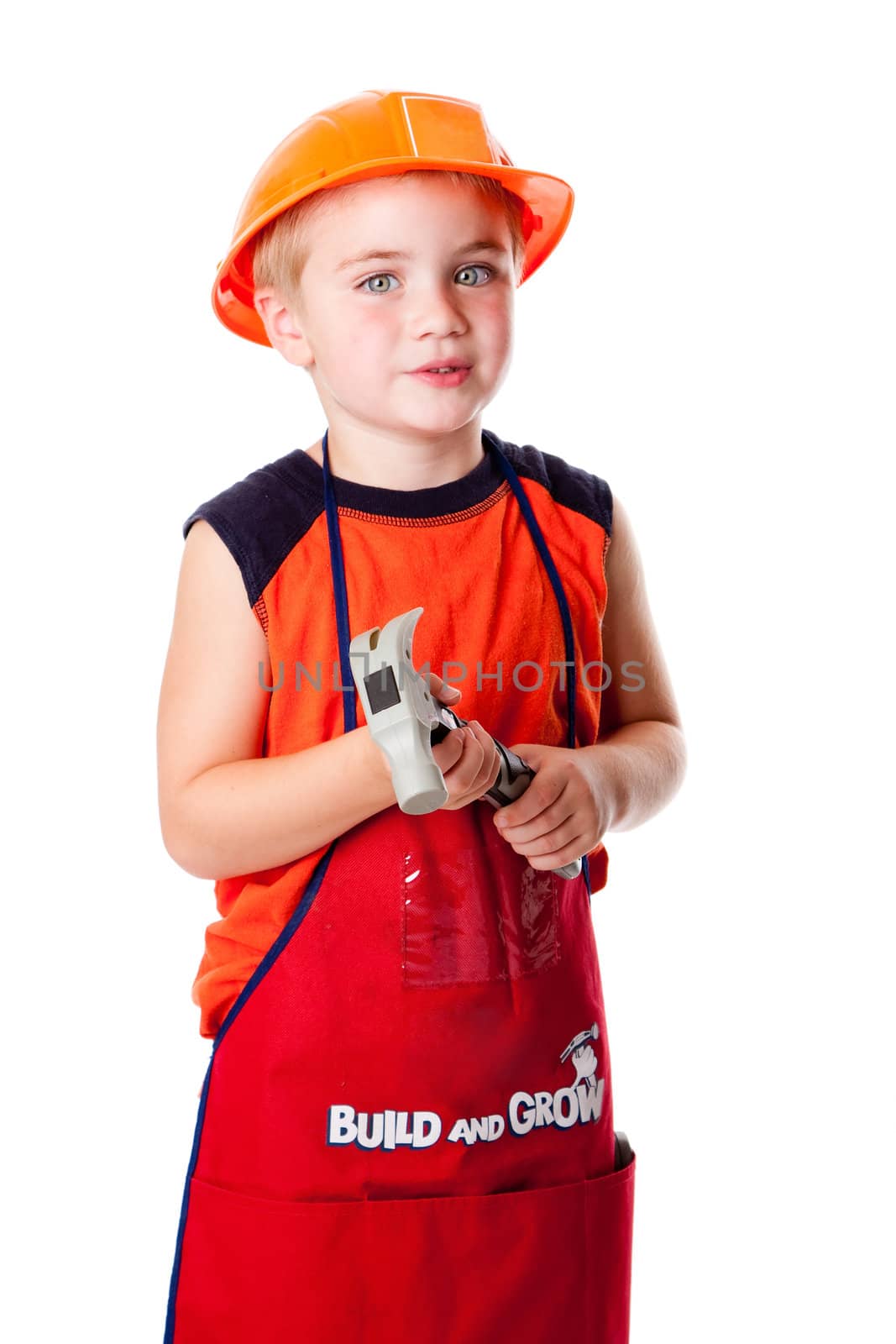 Little Caucasian boy dressed in orrange with construction helmet and apron with pockets, holding a hammer, isolated.