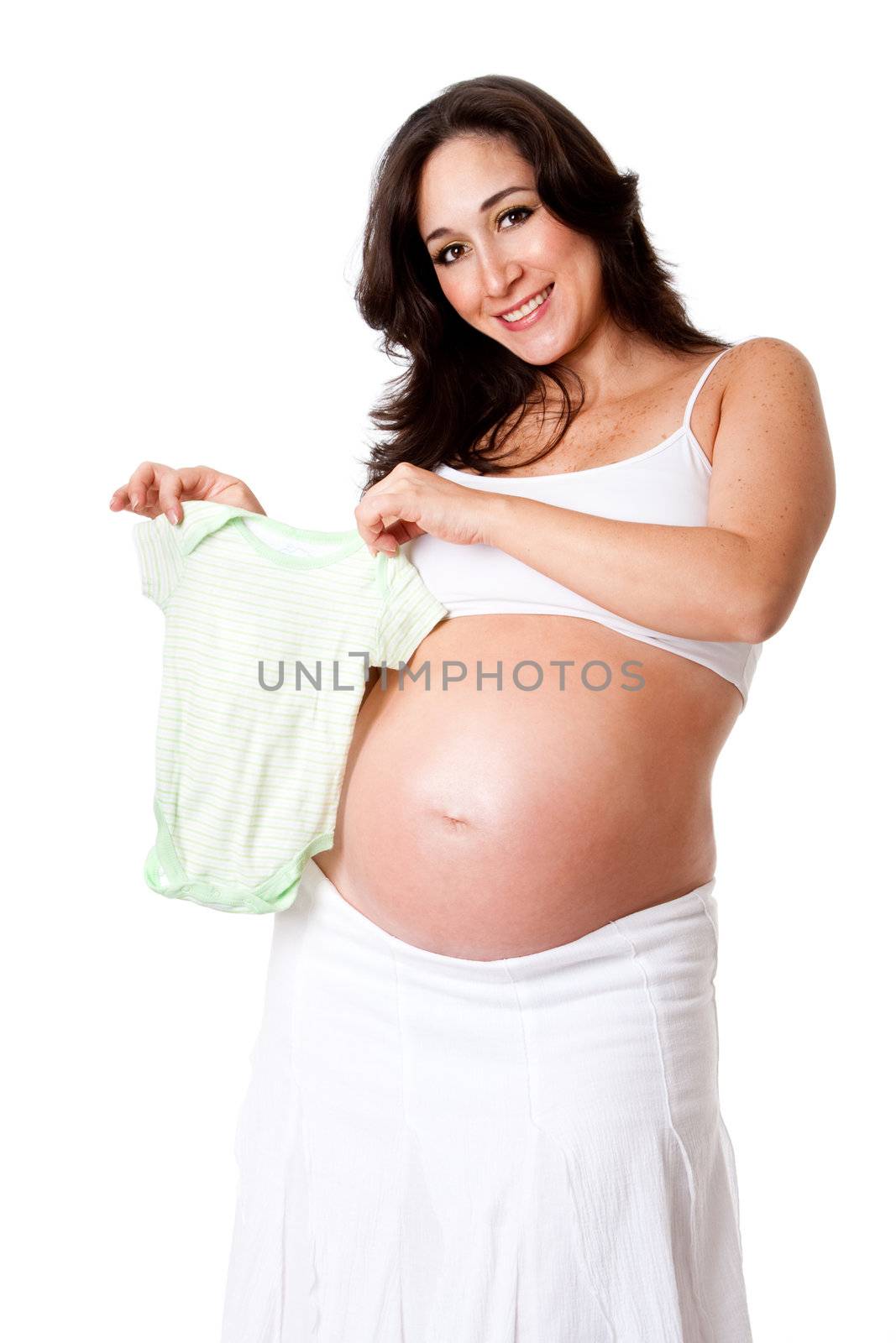 Beautiful happy smiling pregnant woman dressed in white holding a green striped baby bodysuit next to her bare belly, isolated